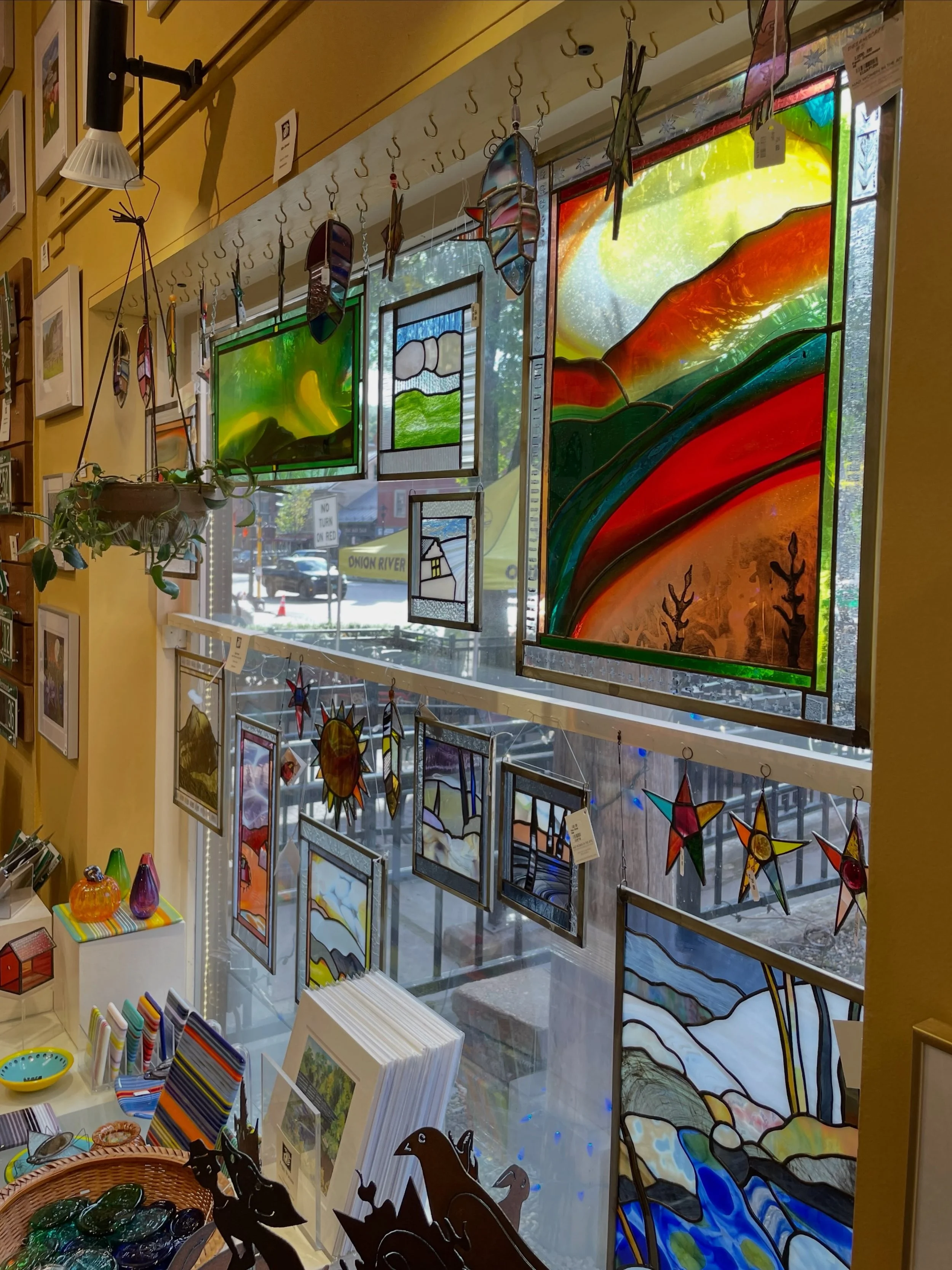 The sun is out just in time to highlight a new delivery of glass work by Elga Gemst, aka The Mad Woman in the Attic.  Come see how her flowers, stars, and feathers sparkle next to the beautiful panels she makes from sheets of blown glass. ✨