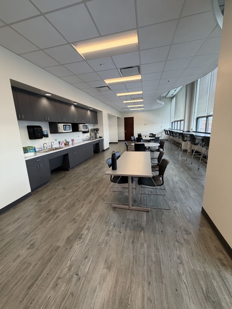 Renovated lounge and dining room completed by Expert Building Maintenance, Inc., featuring updated flooring, cabinetry, lighting, seating, and commercial interior finishes.