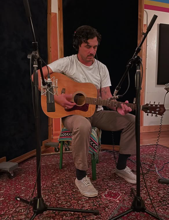 musician with guitar and microphones in studio