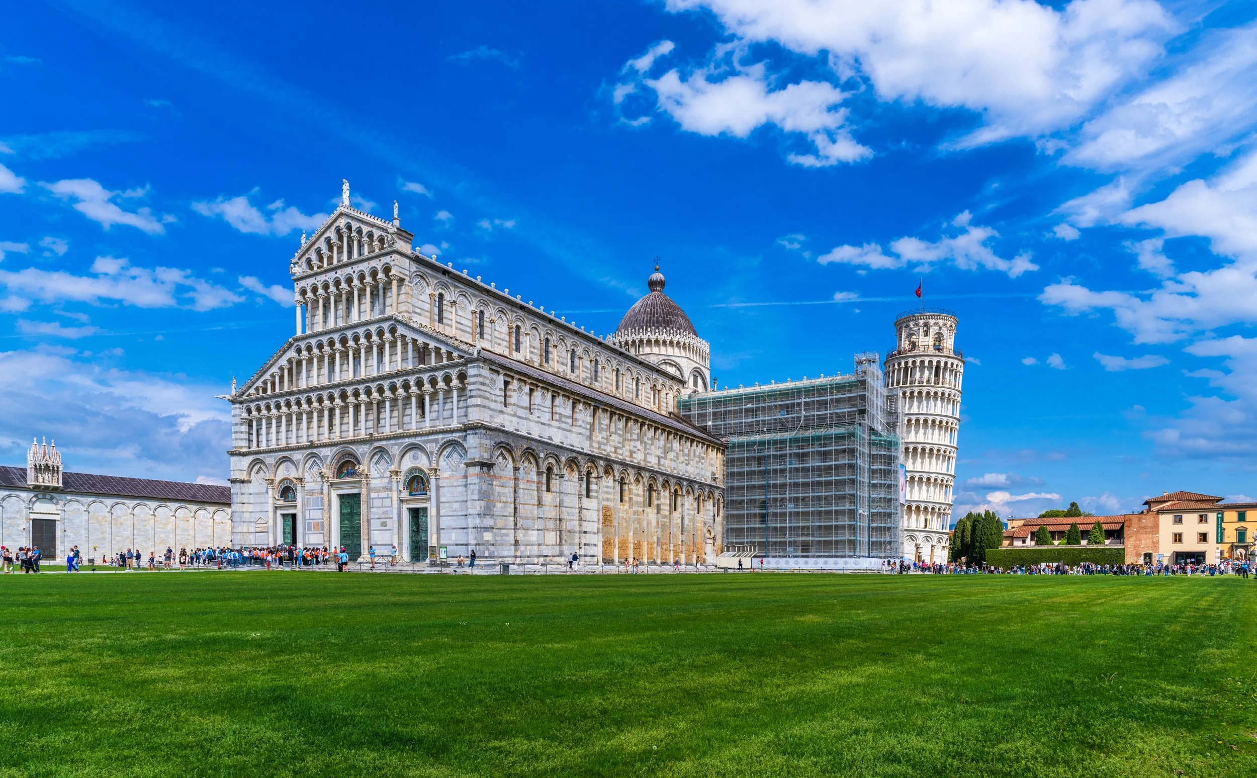 A vibrant panoramic view of the Leaning Tower of Pisa and Pisa Cathedral in Piazza dei Miracoli, Tuscany, Italy. Fine art travel photography capturing one of the world's most iconic UNESCO World Heritage Sites under a brilliant blue sky.