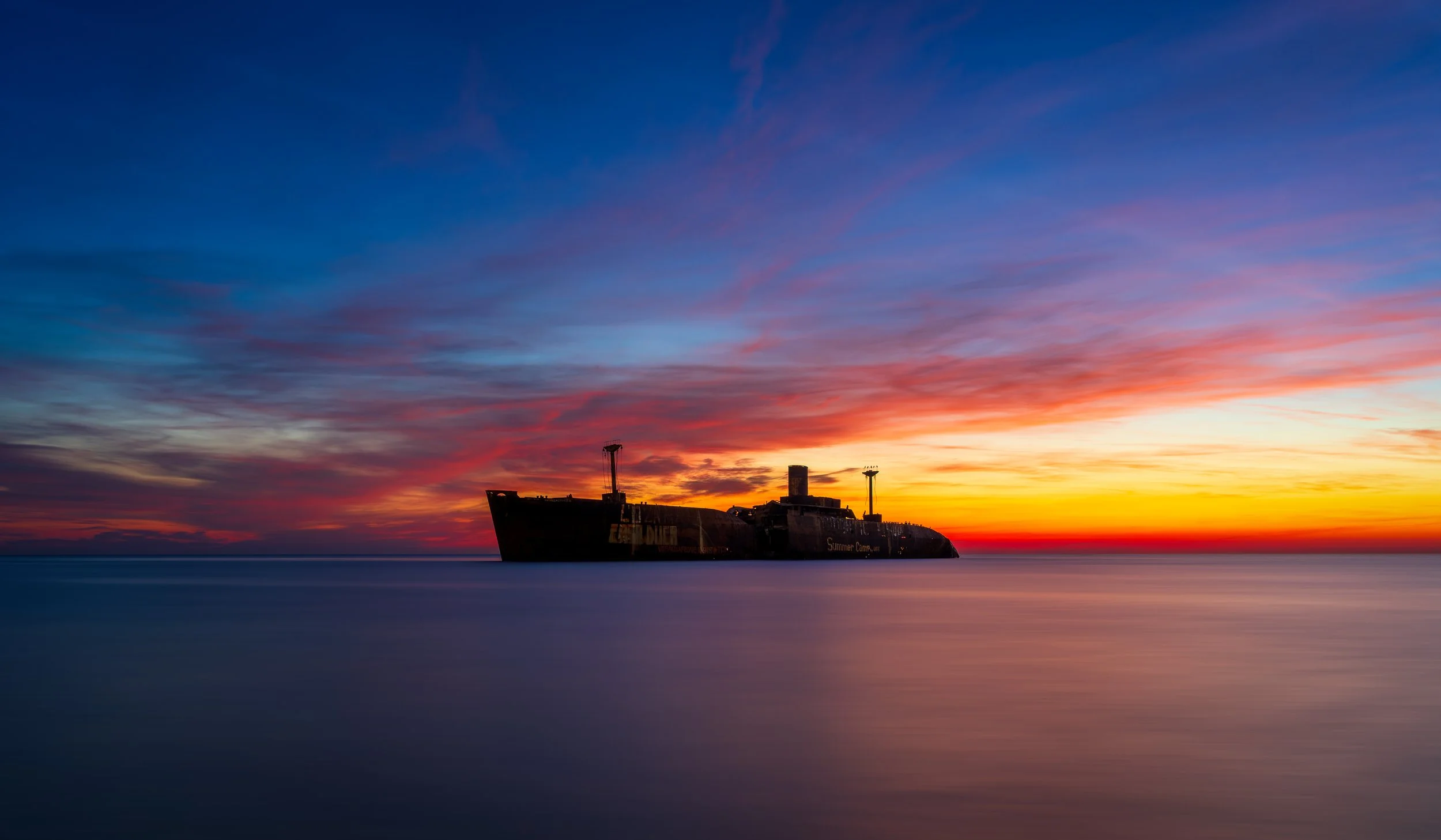 The iconic MV Evangelia shipwreck is silhouetted against a spectacular sunrise off the coast of Costinești, Romania, on the Black Sea. Captured using a long exposure technique, the calm, silky water contrasts beautifully with the weathered vessel whi