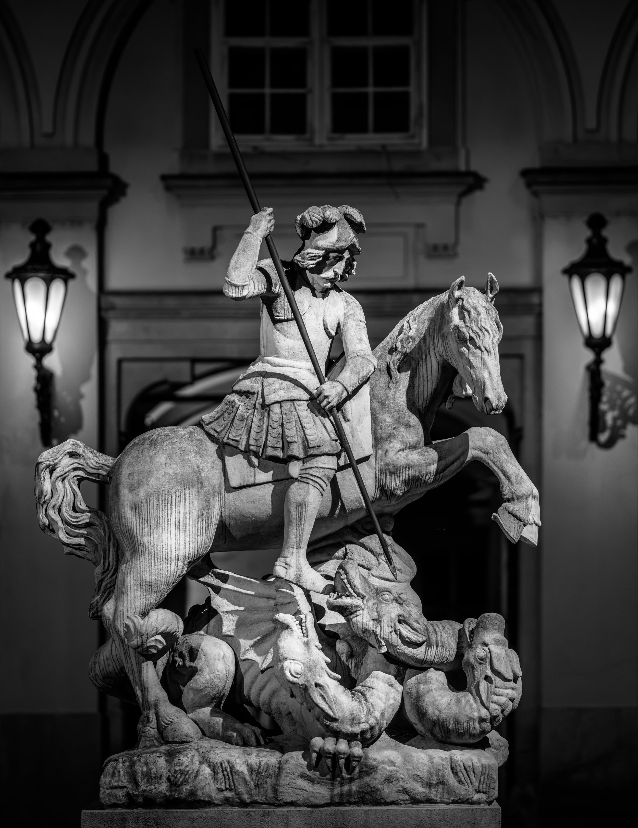 A dramatic black and white photograph of the Saint George and the Dragon statue at the Primatial Palace in Bratislava, Slovakia. Fine art travel and architectural photography capturing one of the city's most iconic Baroque sculptures in timeless mono