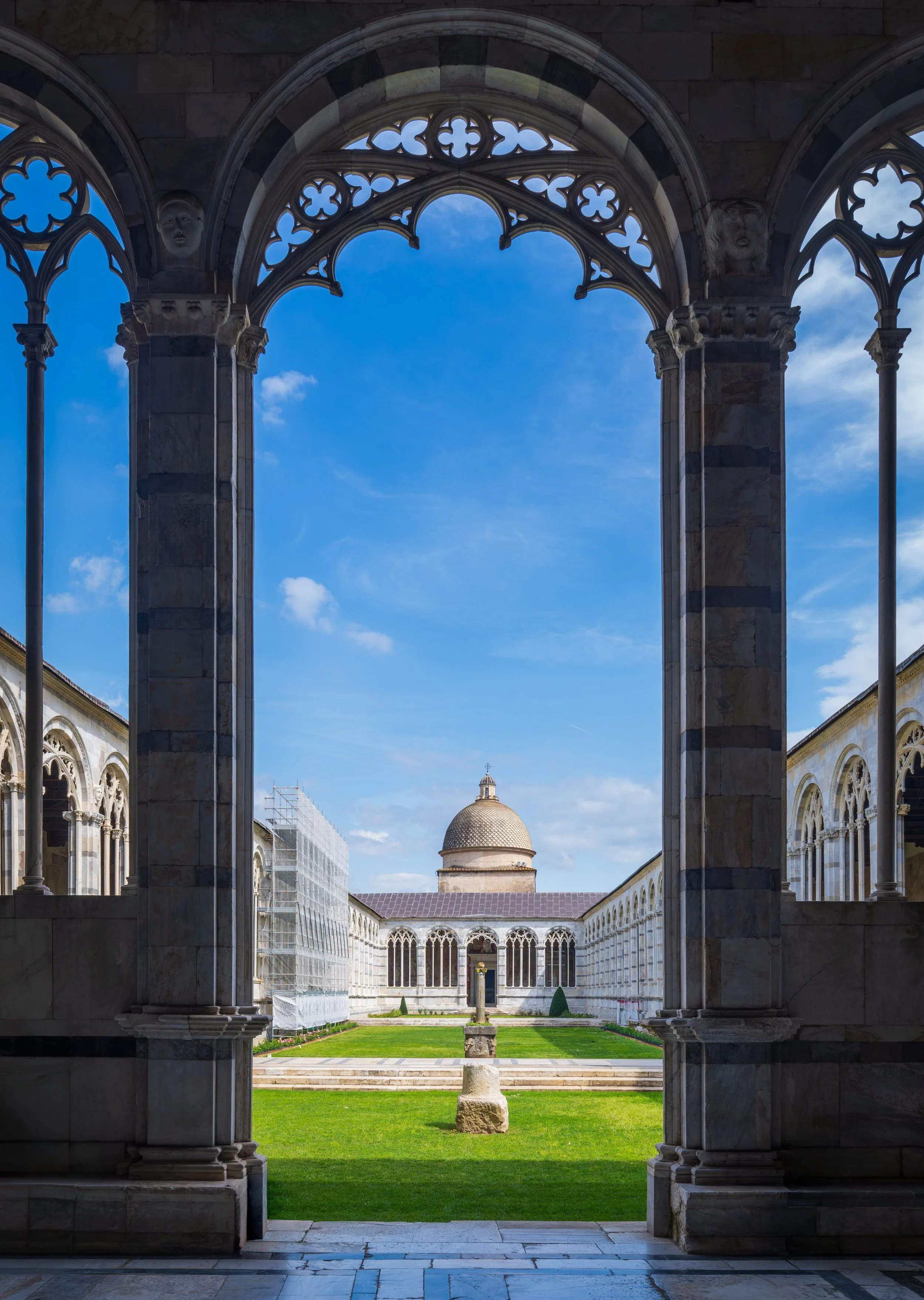 A symmetrical view through the Gothic arches of Camposanto Monumentale in Pisa, Italy, overlooking the peaceful cloister and the dome of Pisa Cathedral. Fine art architectural photography capturing the elegance of one of Tuscany's most remarkable UNE