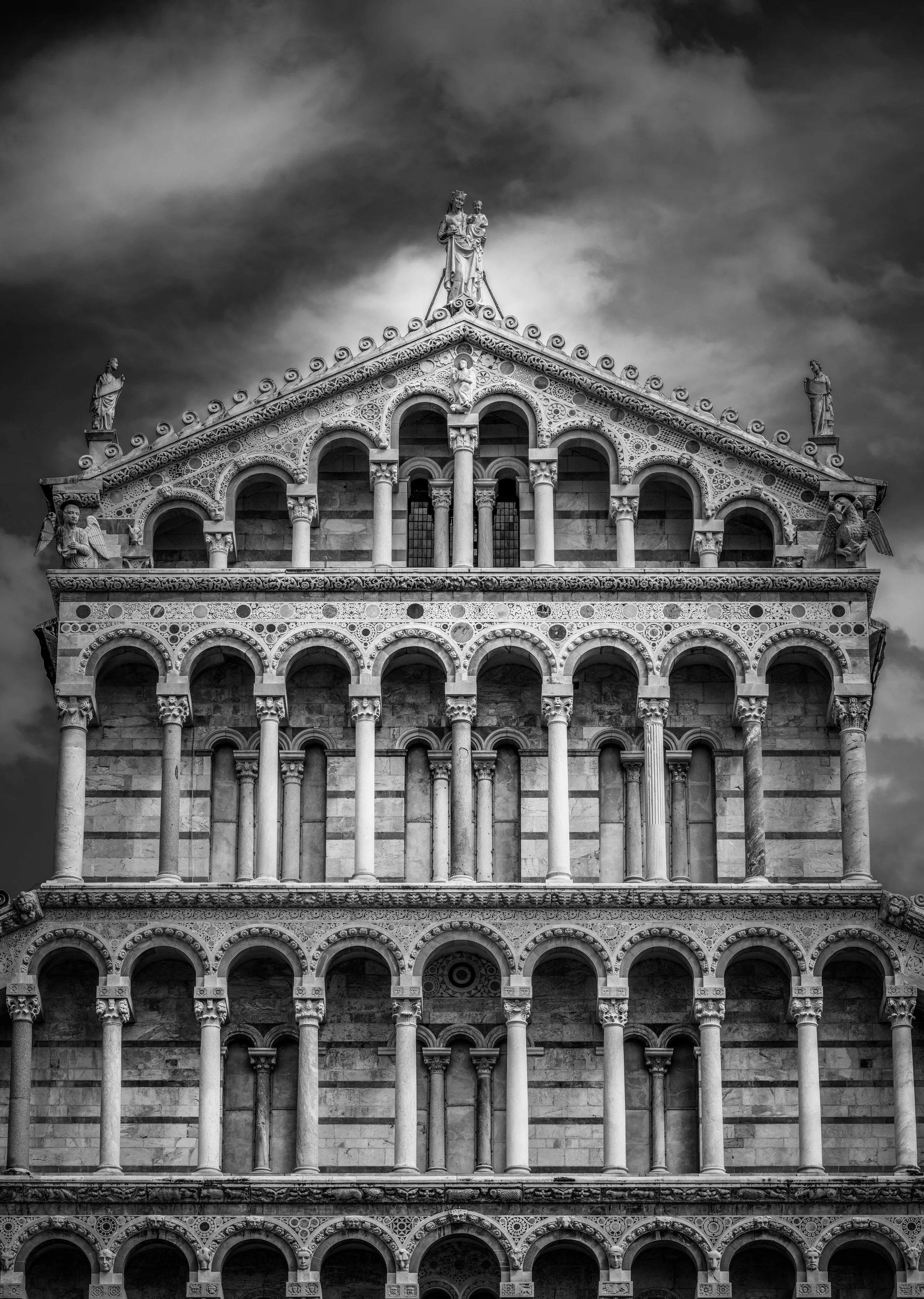 A dramatic black and white close-up of the magnificent façade of Pisa Cathedral (Duomo di Pisa) in Piazza dei Miracoli, Italy. Fine art architectural photography highlighting the cathedral's intricate Romanesque design and one of Tuscany's most iconi