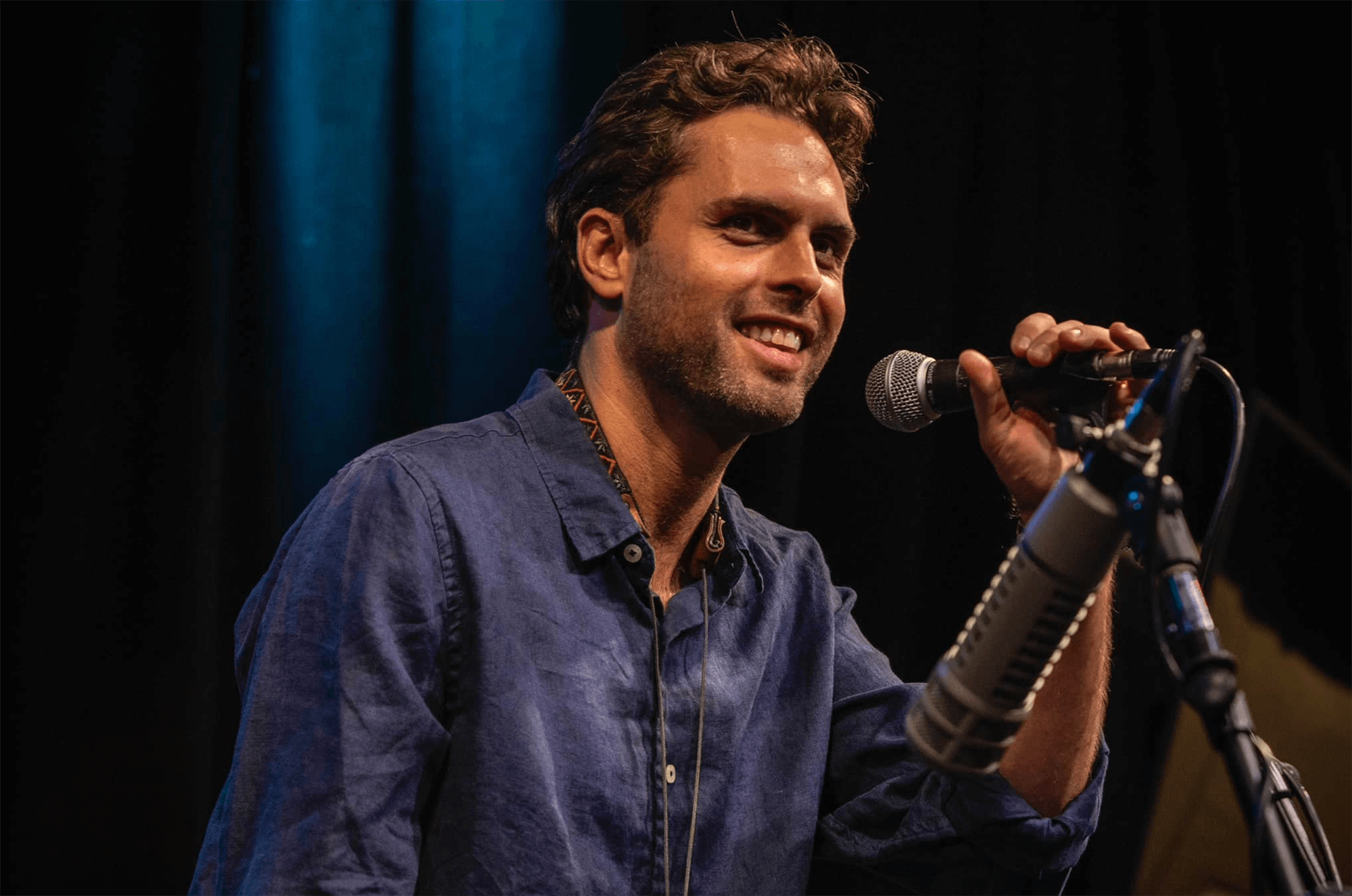Ben Flocks smiling while holding a microphone on stage.