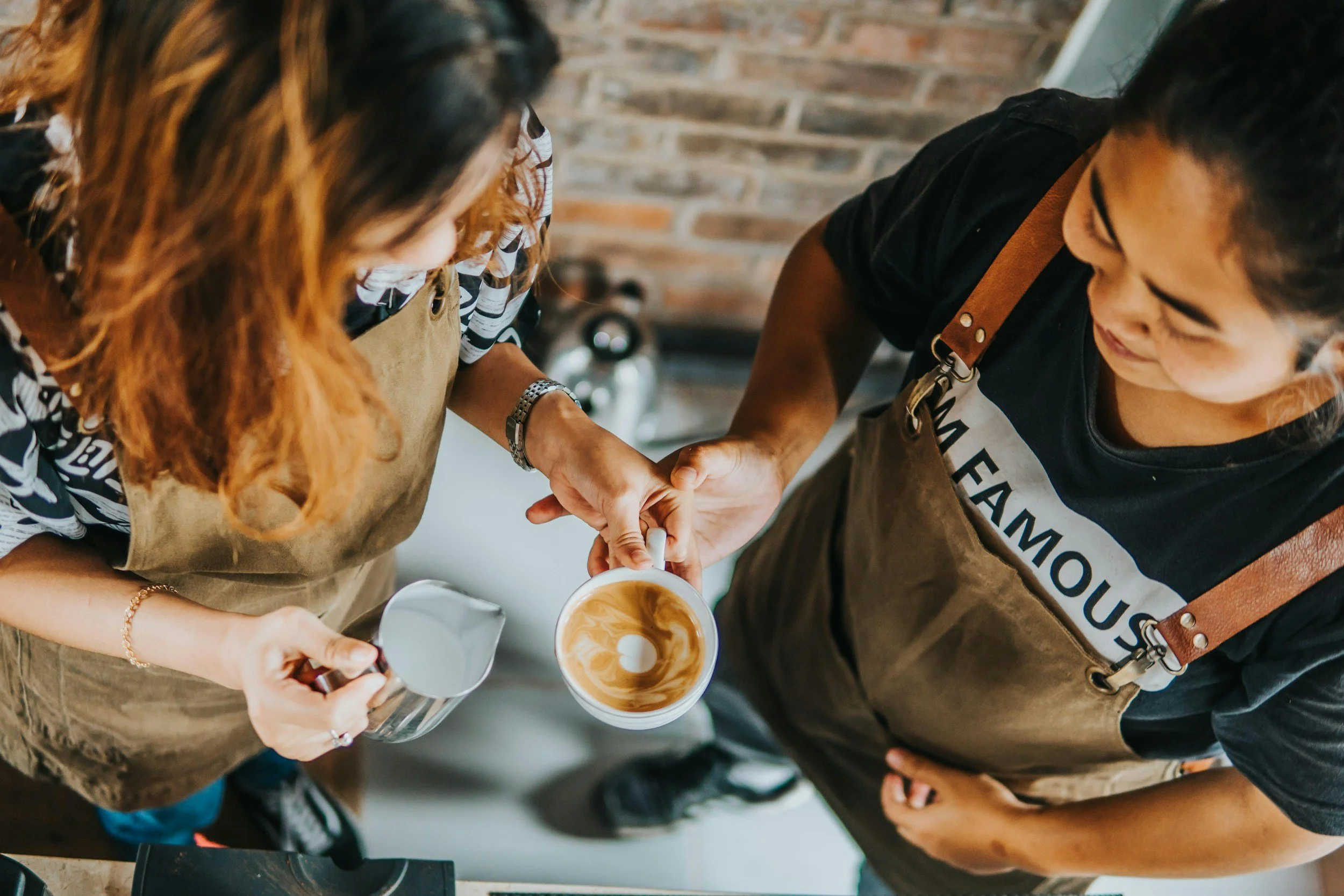 Baristas crafting latte art at Café Corazón, Kansas City’s premier Latin and Indigenous-owned coffee shop, showcasing specialty espresso drinks, artisanal coffee craftsmanship, and community-driven café culture in a warm, creative space.