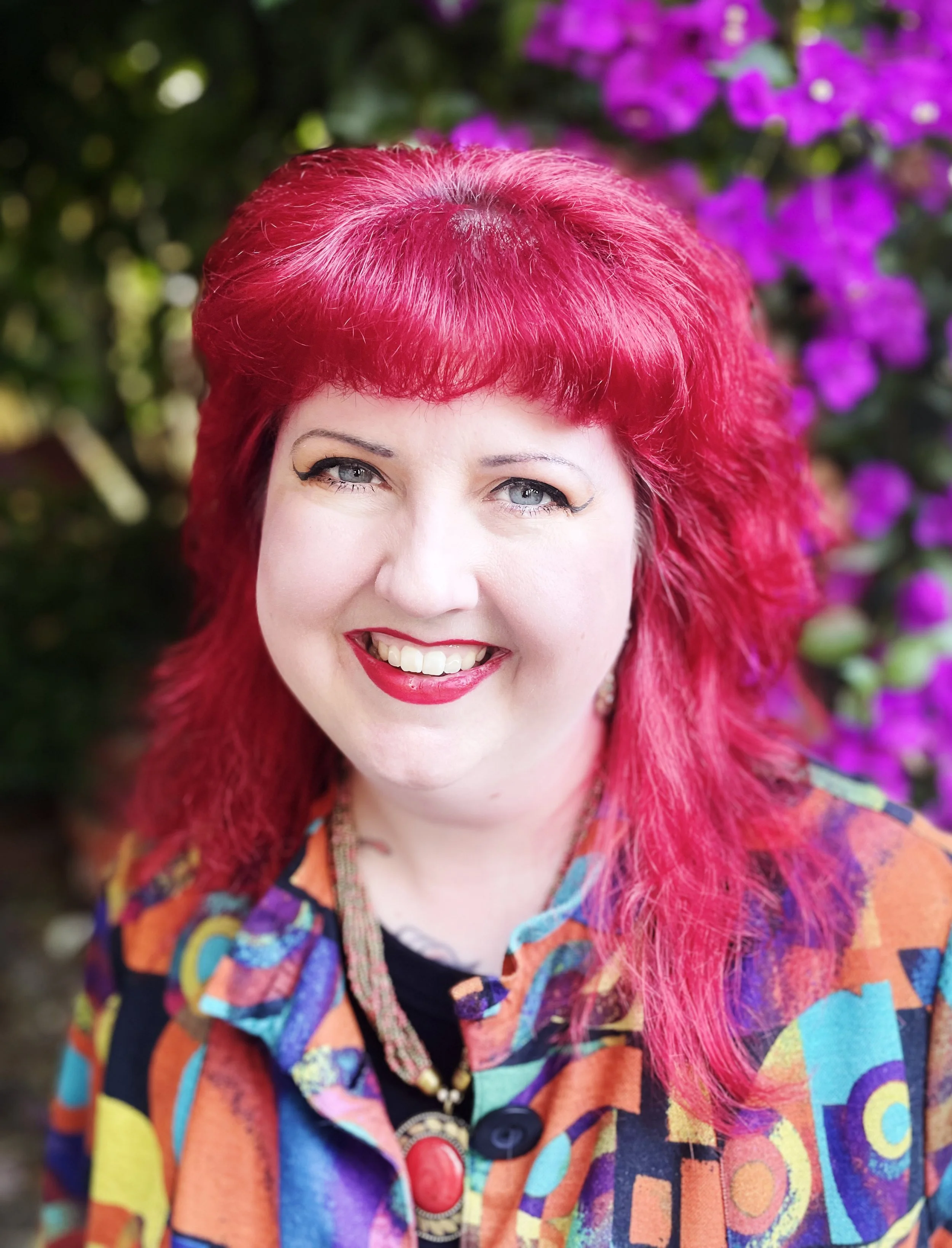 A person with bright red hair smiles.
