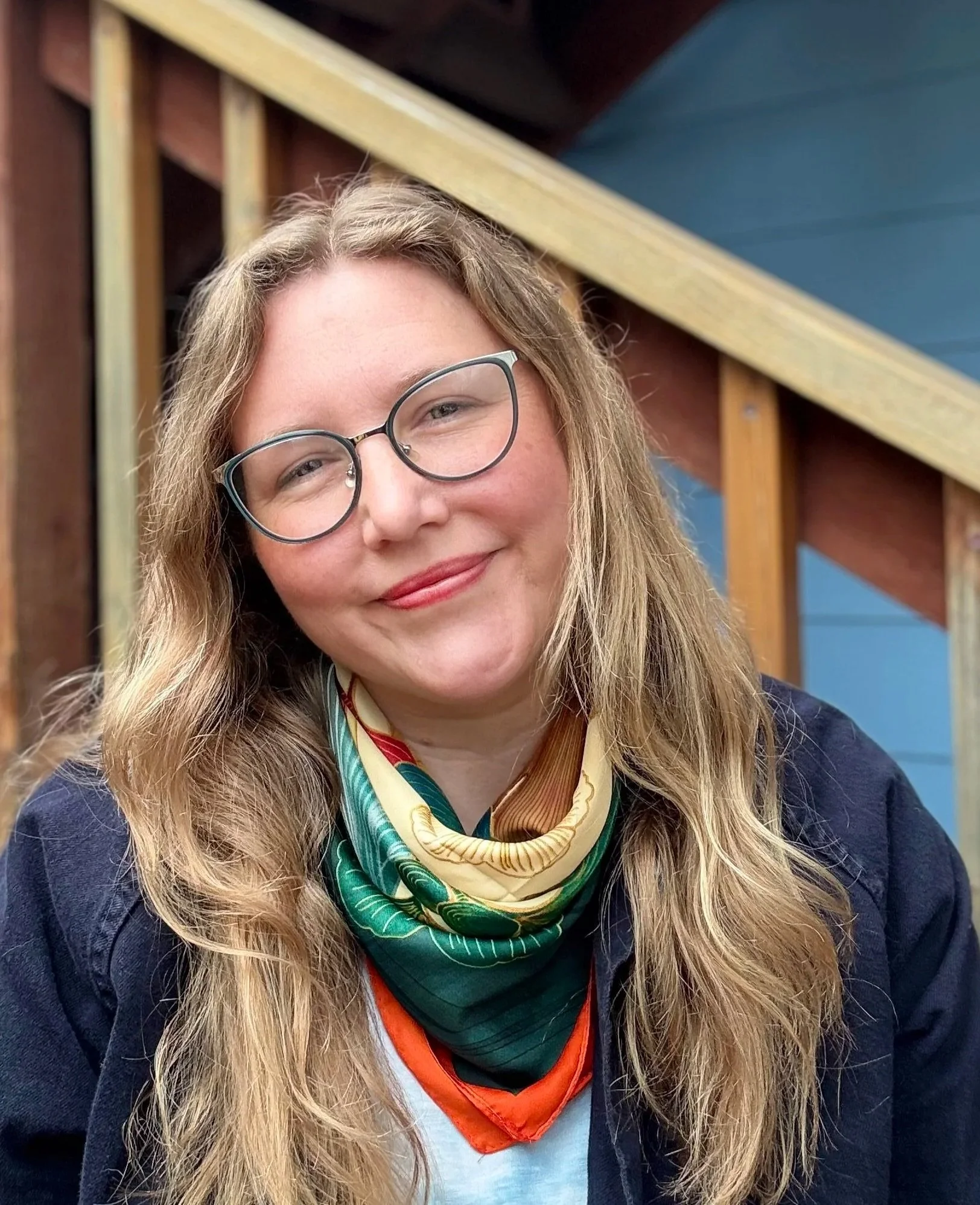A person with long hair wearing glasses and a colorful scarf.