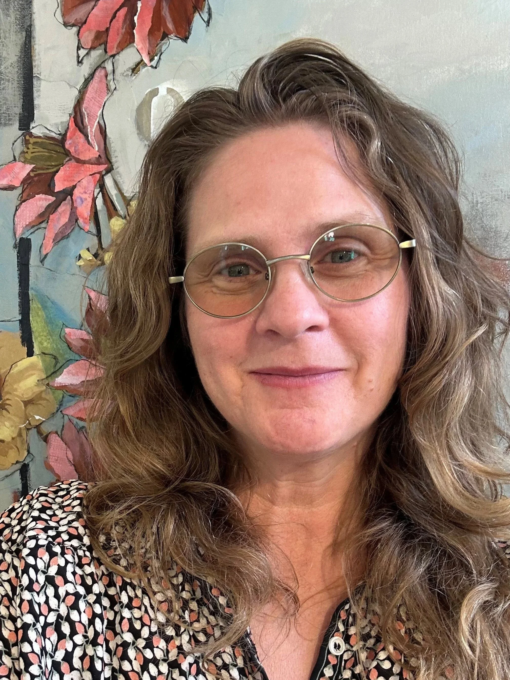 A woman with long brown hair and glasses.
