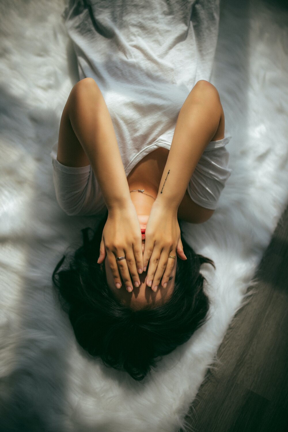 Stock picture of woman laying alone on bed and covering her face. Photo: Anthony Tran/Unsplash