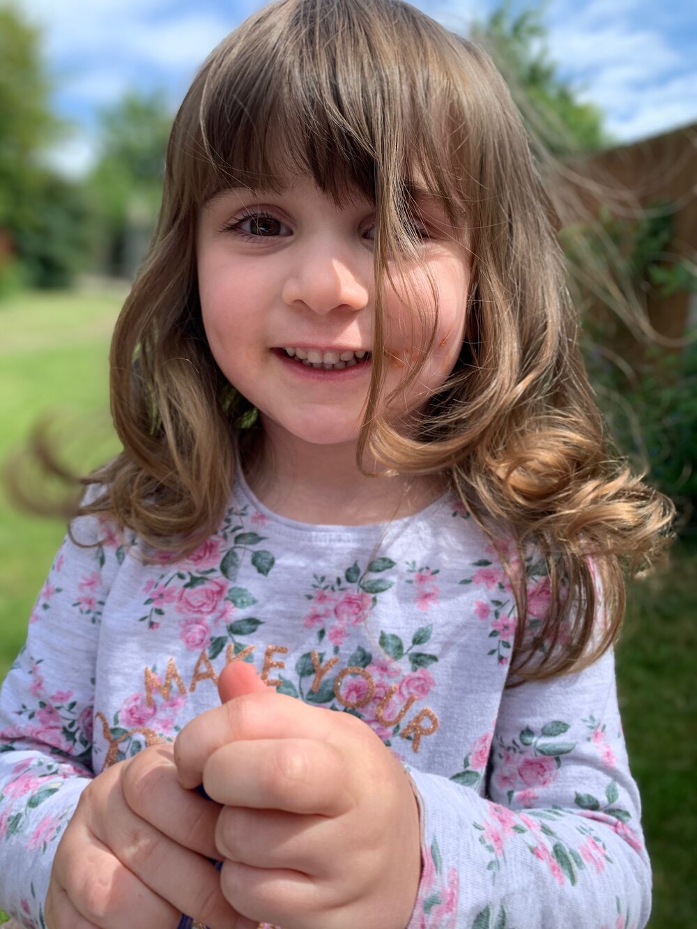Millie smiling at the camera whilst playing in the garden, aged 3.5. Photo: Lacuna Voices.