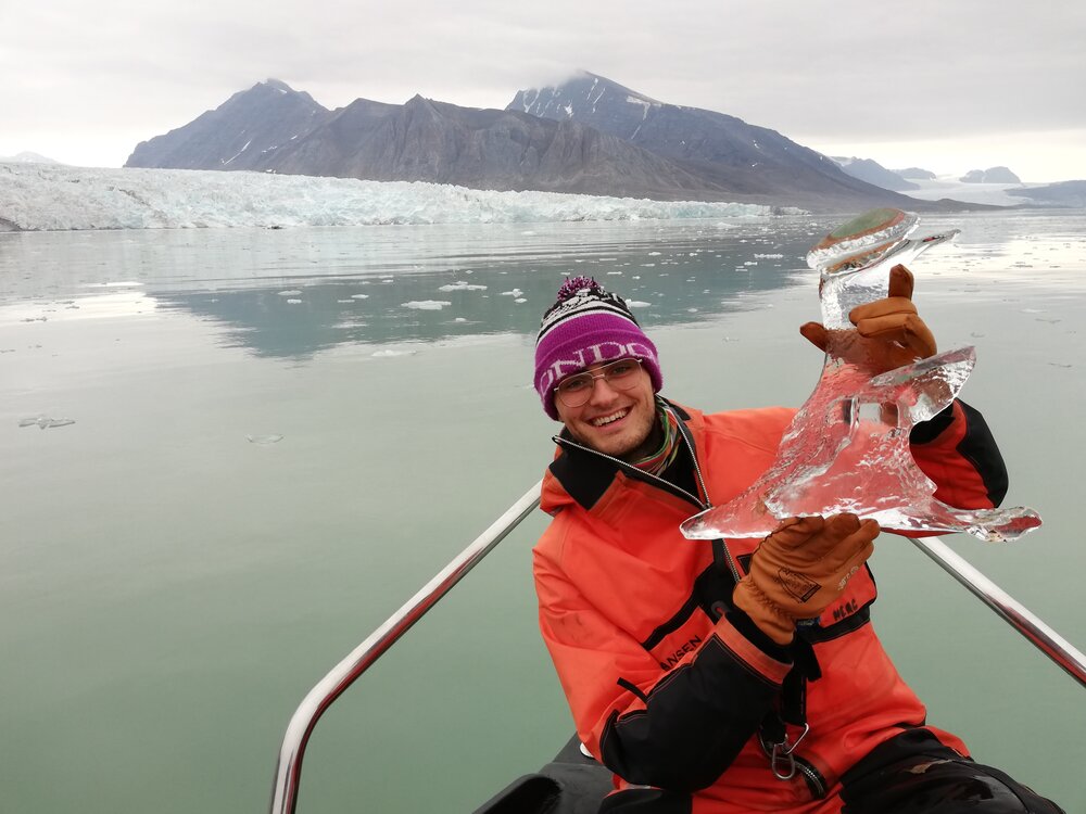 PhD student Robbie Mallett holding a small iceberg near a glacier in Svalbard on a scientific expedition. Photo: Robbie Mallett