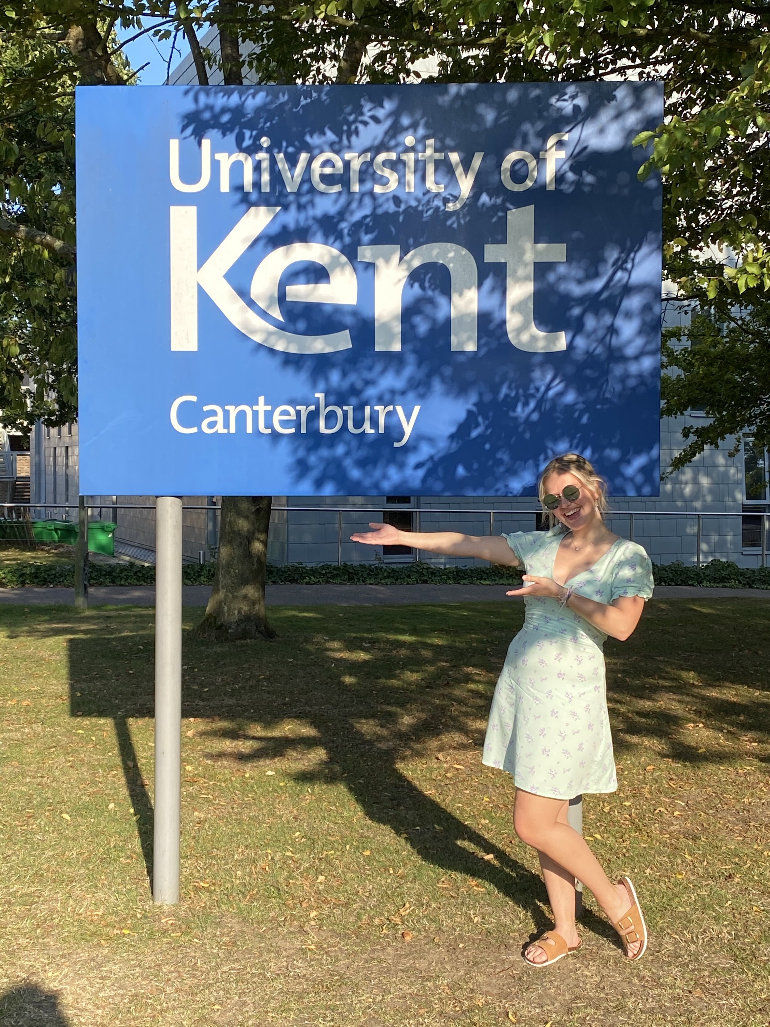 Graduating from University of Kent in 2020, Claudia can be seen in a short blue dress against the university's sign. Claudia Parker .jpeg