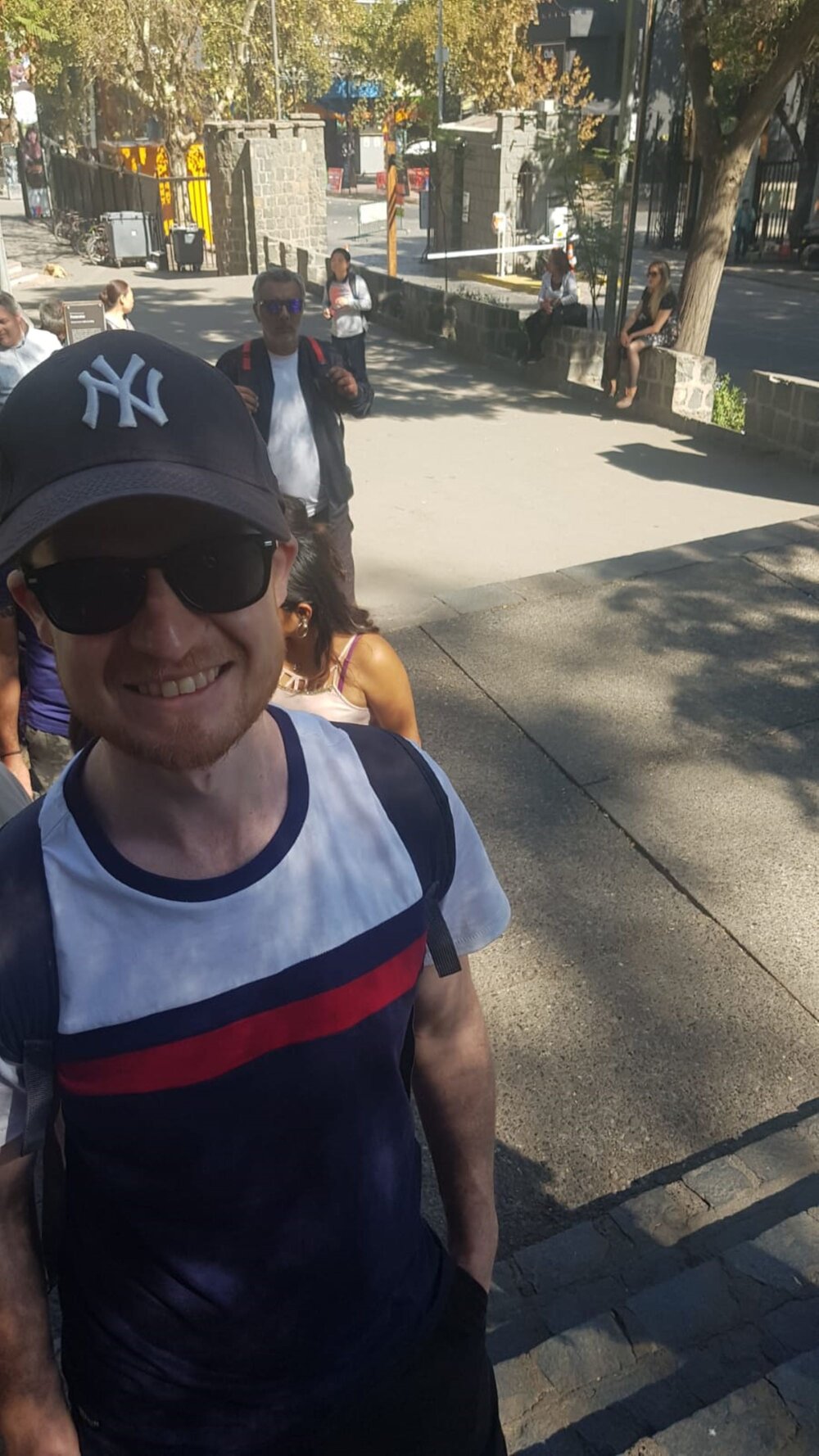 Enjoying a queue to see the sites in Santiago 2019. It's sunny and he's wearing a cap and sunglasses. Photo: Alex Waite