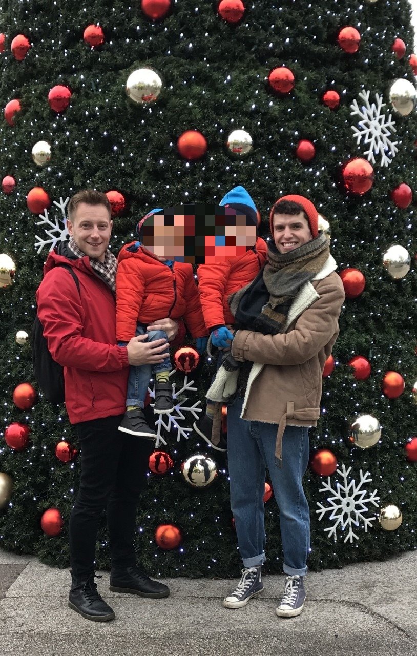 Damian and Andrew holding their sons in front of a giant Christmas tree at Thomas Land. Photo: Damian Kerlin