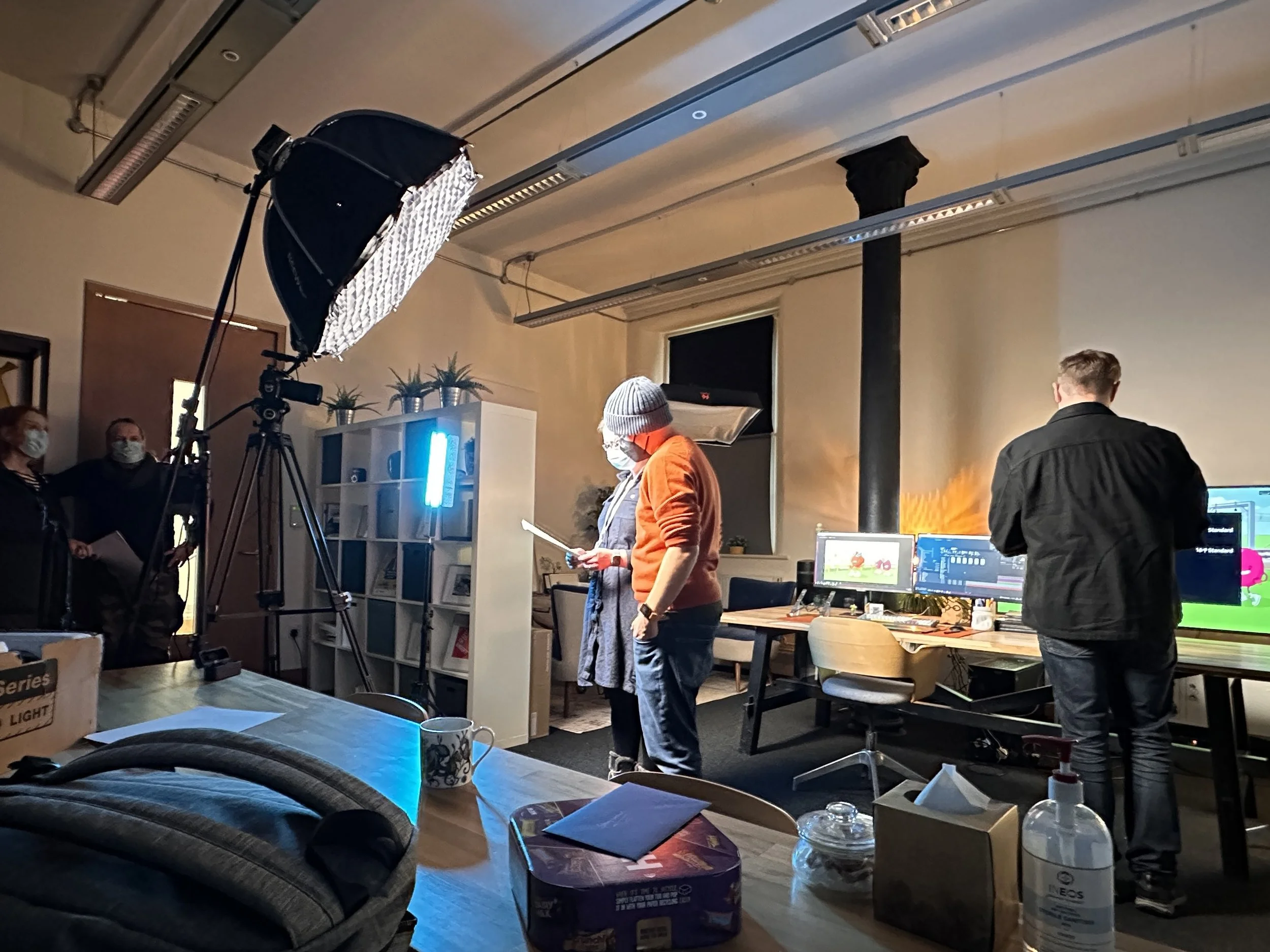 Photo of Chicken Fruit director Jonny on a film set, standing in front of a big box light, reading a script before he has to deliver some lines.