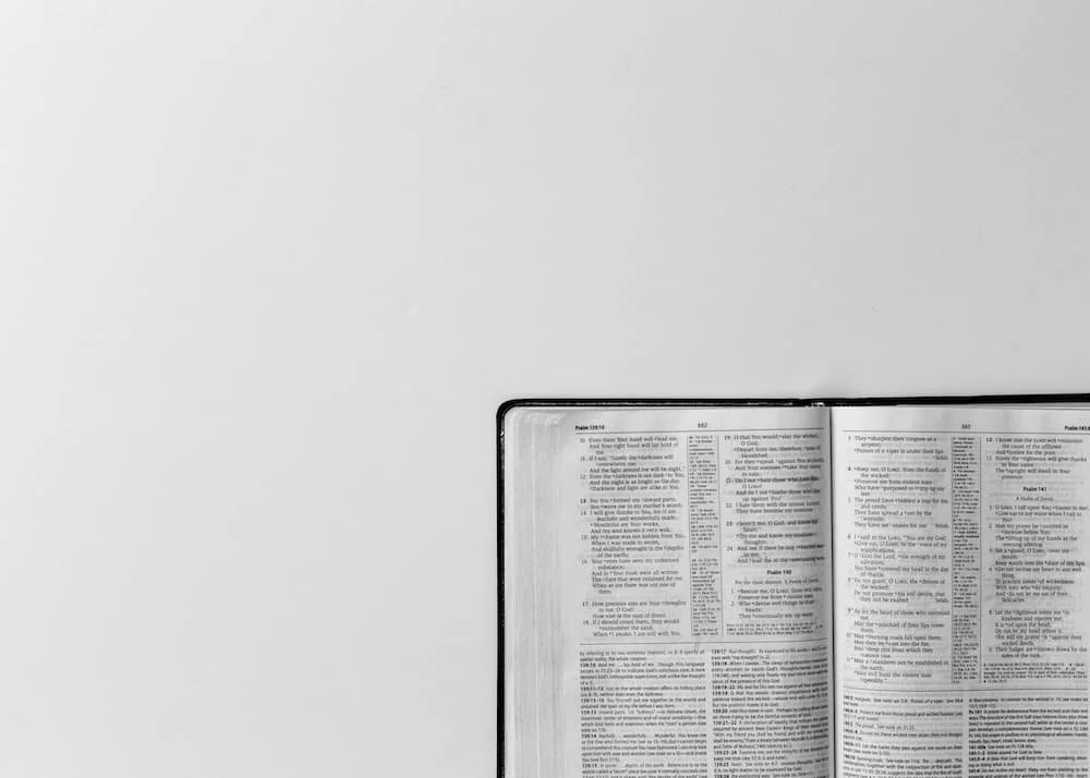 Una Biblia abierta en el Libro de los Salmos, con texto negro sobre páginas blancas, colocada sobre una superficie gris.