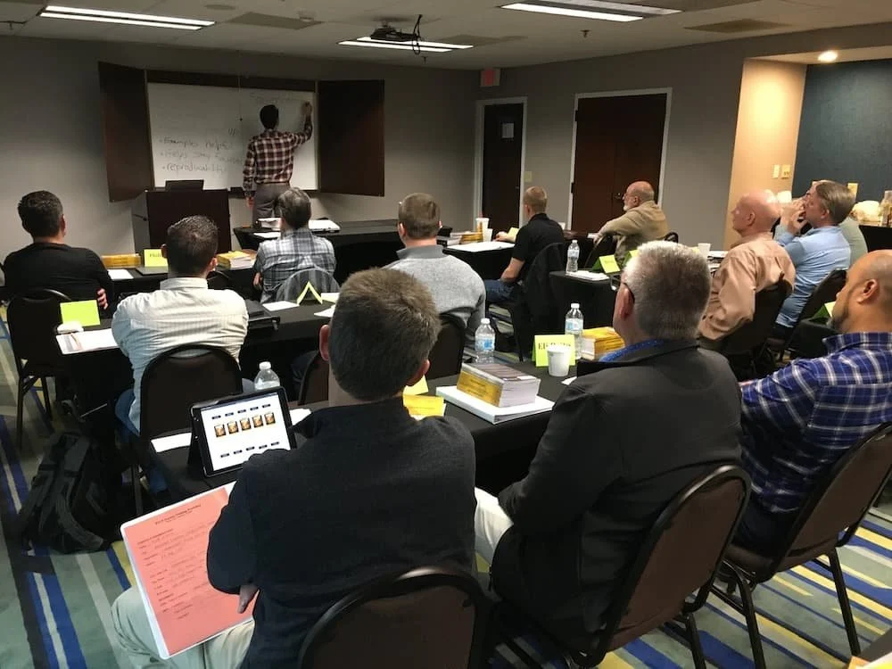 A teacher at the front of a group of missionaries gies biblical teaching.
