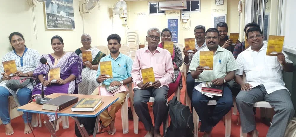 Pastors and church leaders in India holding their Telugu-language BTCP training manuals during a class session.