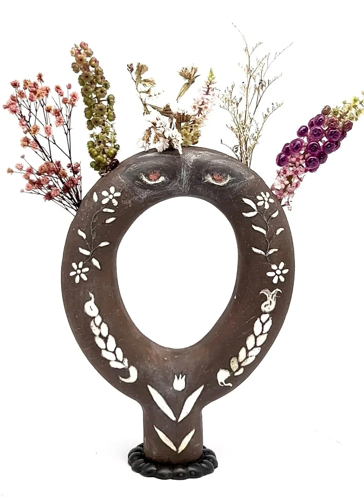 Formed through tube extrusion and refined by hand, this ceramic vase includes five stem holes and detailed painted imagery including eyes, braids, and floral patterns, uniting function with sculptural surface design.
Medium: Ceramic sculpture
Price: 