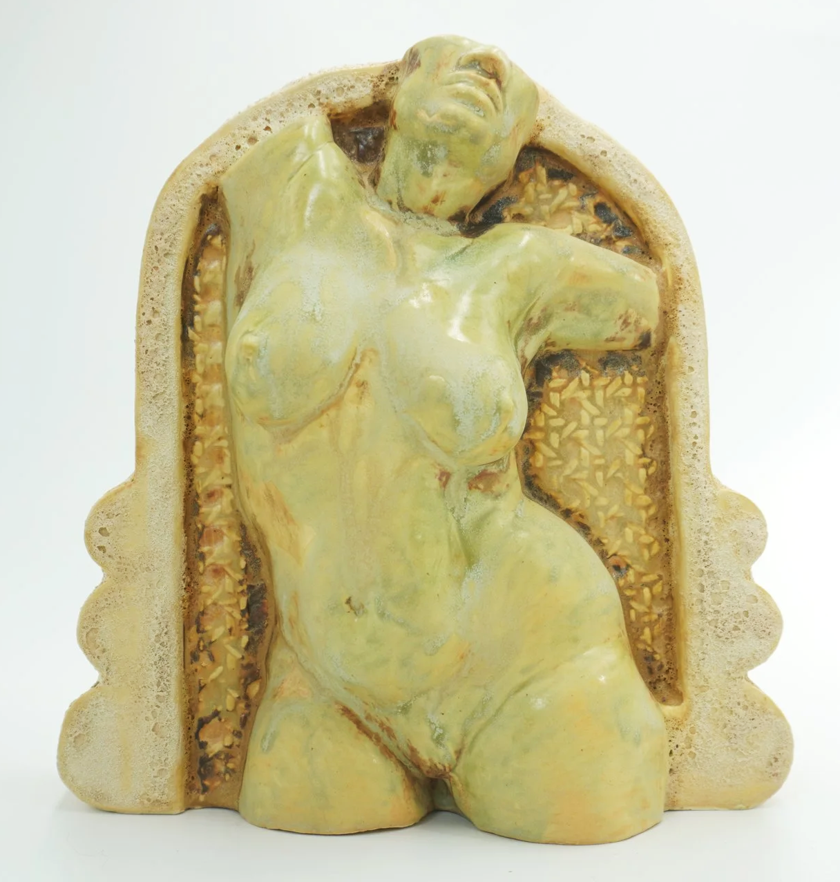 A ceramic figurative watertight vessel developed from an original sculpted form, slipcast and refined with handbuilt details. Several layers of glaze, oxides, cratered textured cathedral frames, and a caned webbing background behind the figure. Desig