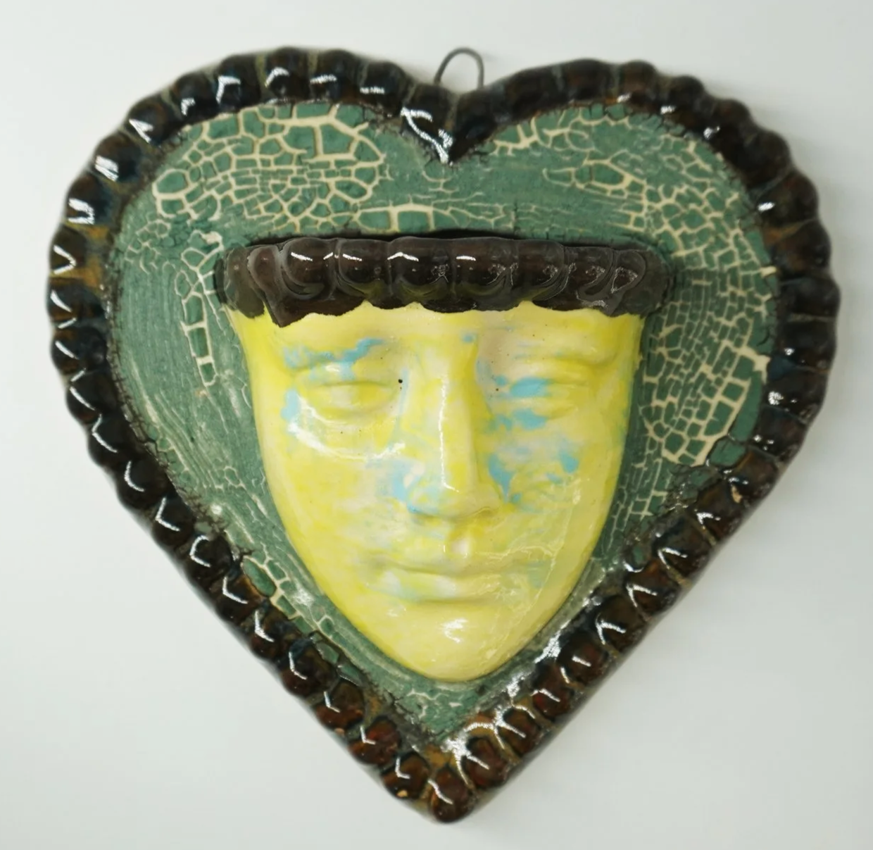 A ceramic face vase formed from an original sculpted model, slipcast and refined by hand. Finished with layered glazes, a heart-shaped frame, and a built in water-tight opening for keepsakes.

Medium: Ceramic sculpture
Price: $118.00
Dimensions: 5" X
