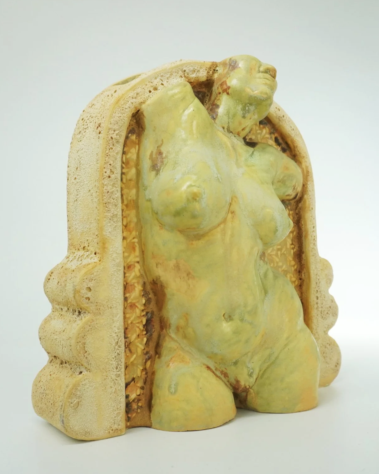 A ceramic figurative watertight vessel developed from an original sculpted form, slipcast and refined with handbuilt details. Several layers of glaze, oxides, cratered textured cathedral frames, and a caned webbing background behind the figure. Desig