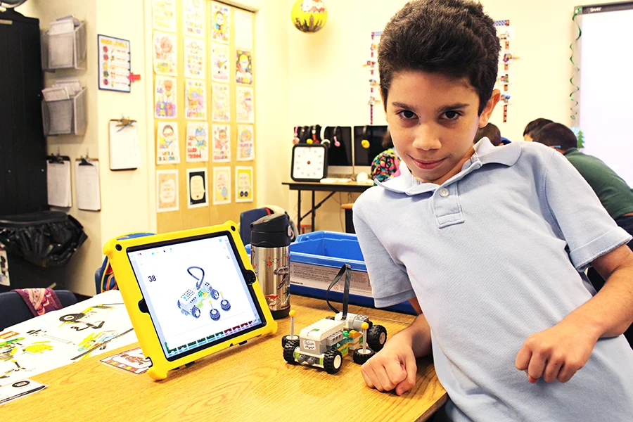 A UCP Downtown/BETA student poses with his robotics project.
