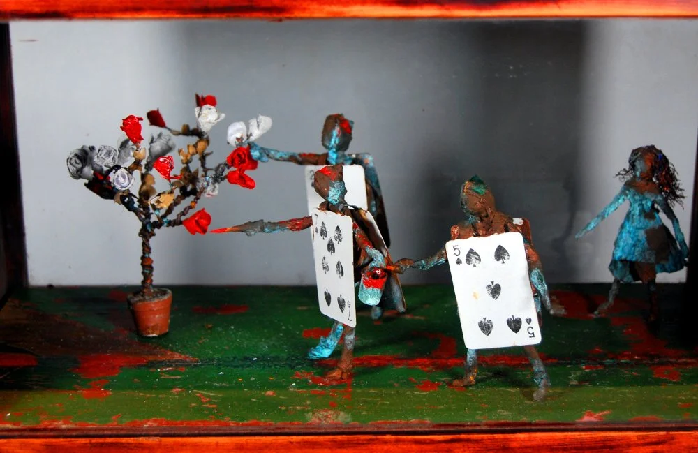  A large rose-tree stood near the entrance of the garden: the roses growing on it were white, but there were three gardeners at it, busily painting them red. Alice thought this a very curious thing, and she went nearer to watch them, and just as she 