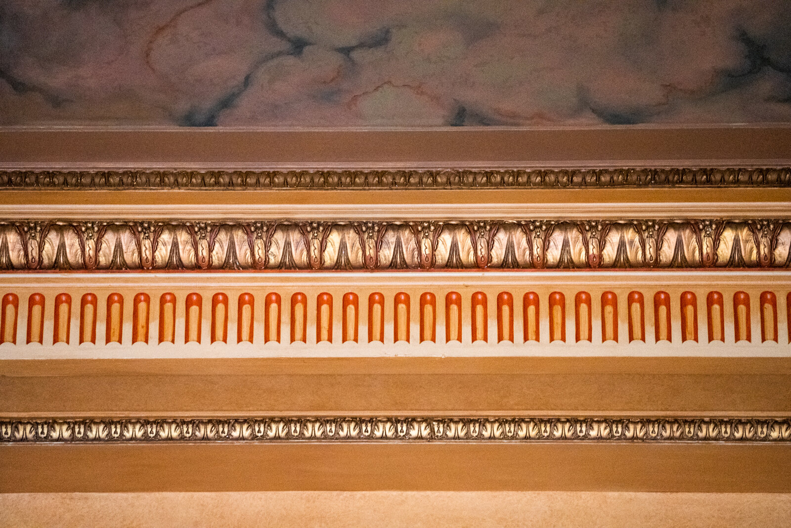  Plaster mouldings with leaf motif and arch pattern, painted gold with red and brown accents   