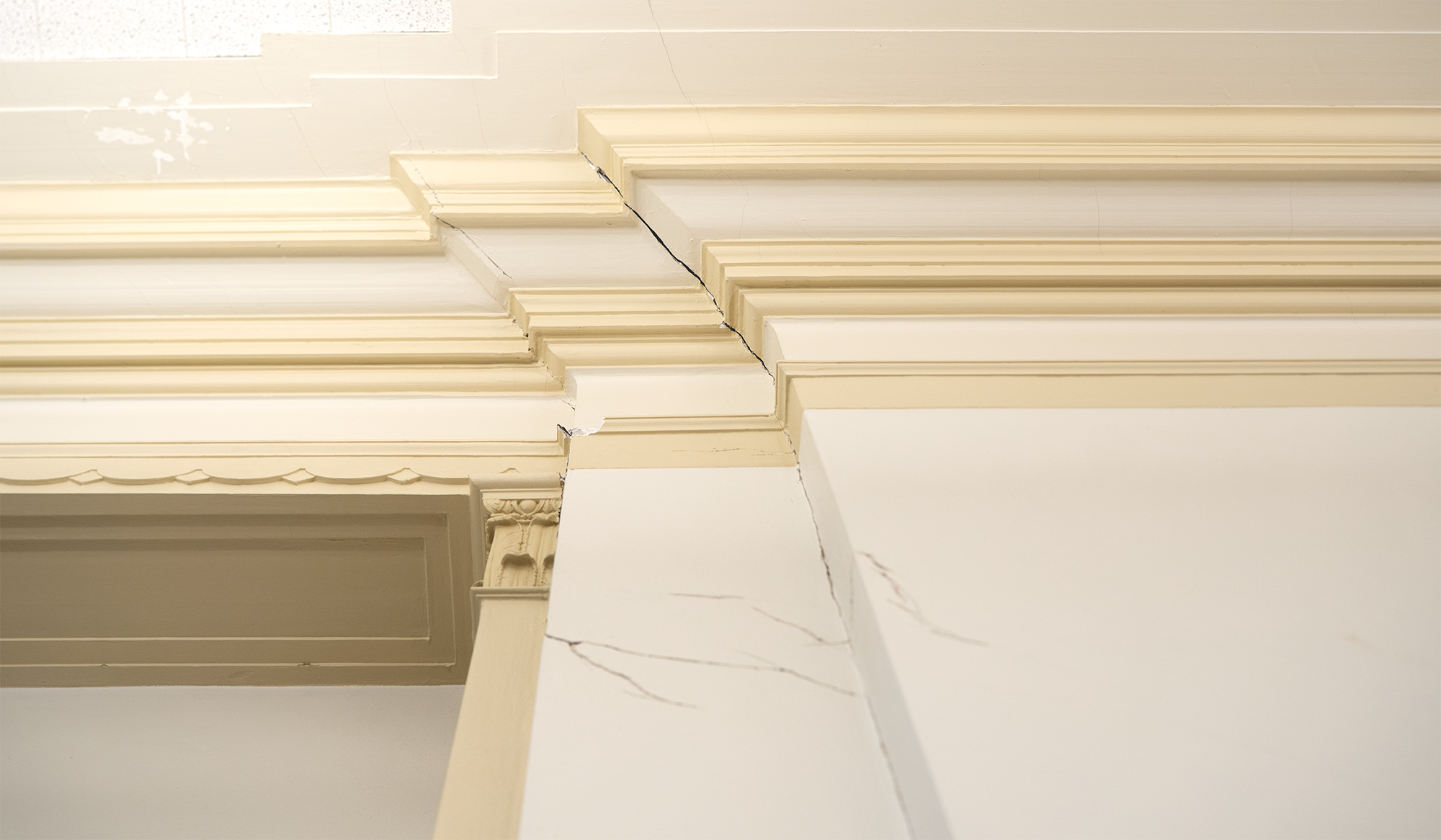Interior architectural detail with beige molding and cracks