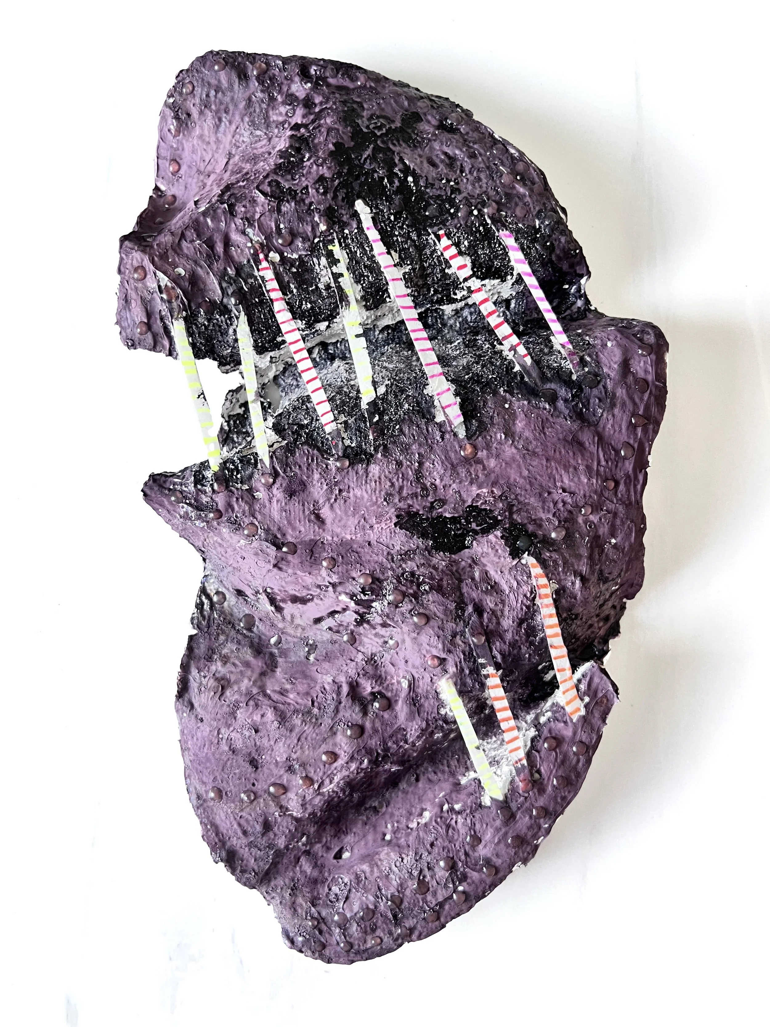 A mixed media art piece featuring a purple and black textured surface with striped paper strips and small beads or dots adhered to it.