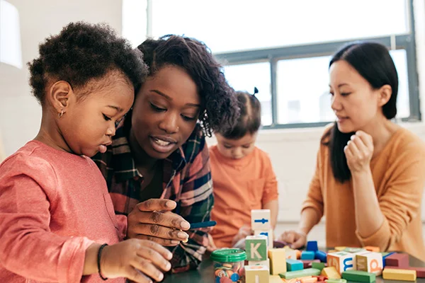 Child care workers with children at play table