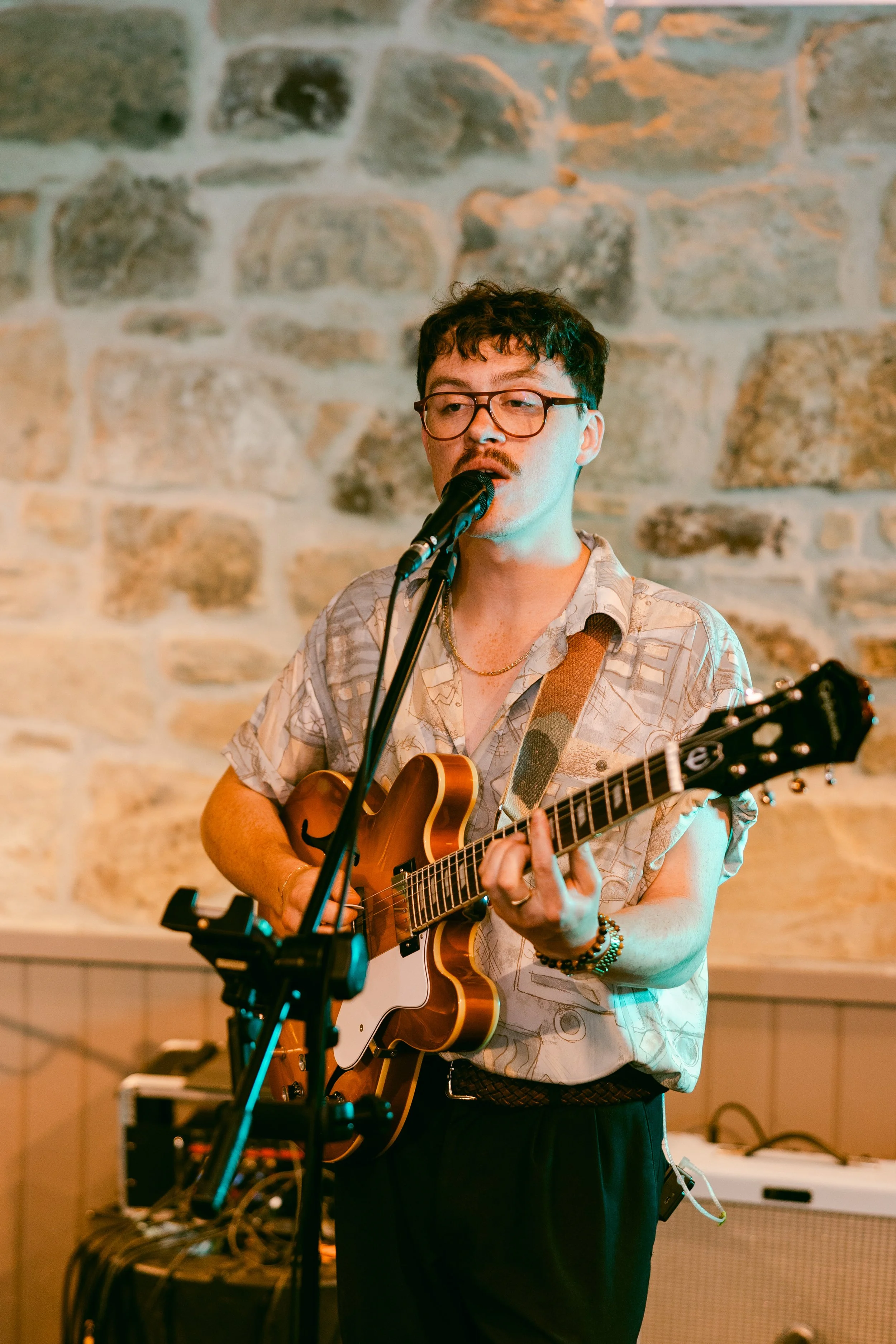 A man with glasses and a patterned shirt playing an acoustic guitar North East wedding band - book the best wedding band - the Gatenby's - Wedding Music