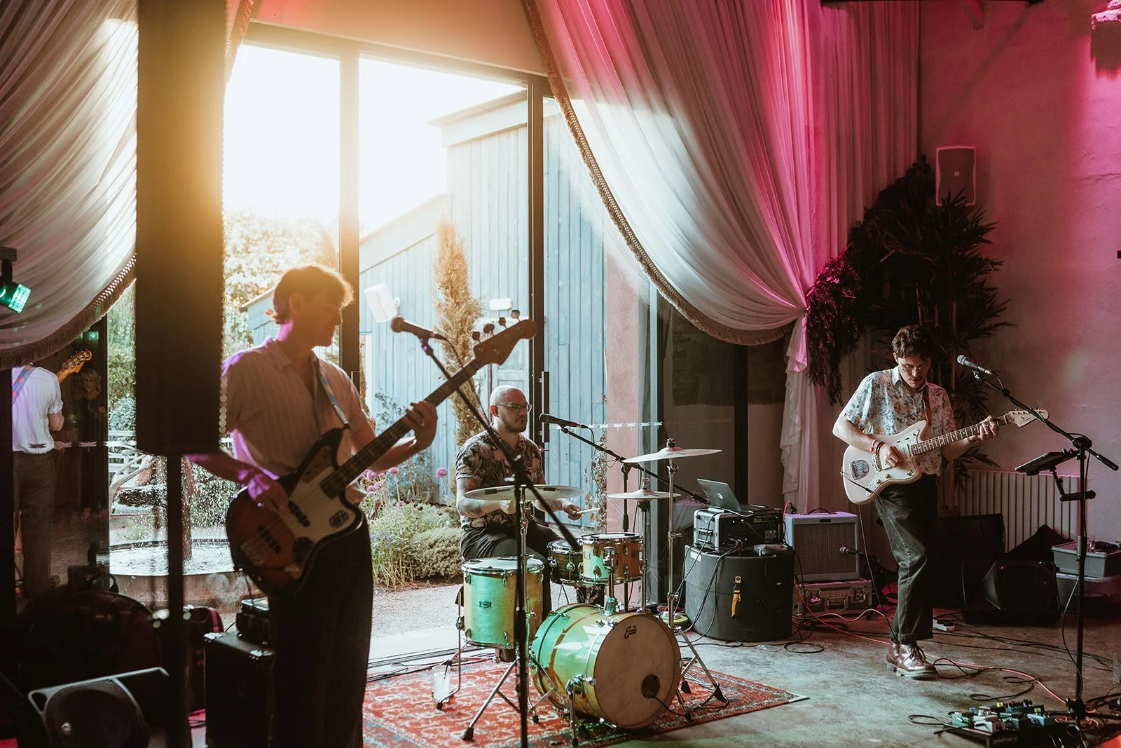 North East wedding band - book the best wedding band - the Gatenby's - Photography by Danny Birell A band performing indoors with two guitarists and a drummer, inside Runa Farm 