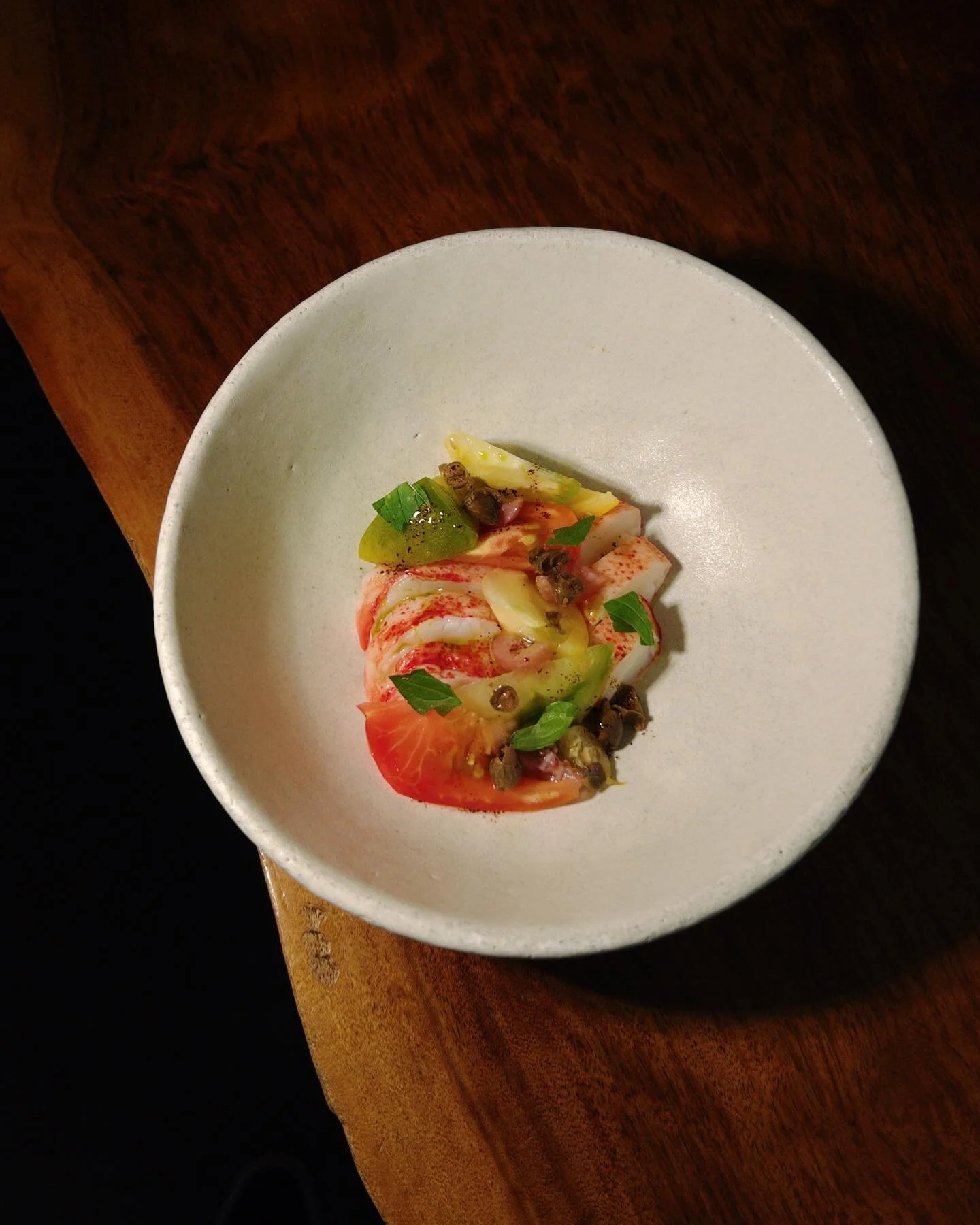 Maine lobster served with heirloom tomatoes and dressed with a vinaigrette made with brown butter, capers, fermented gooseberries, chopped lovage and mint.