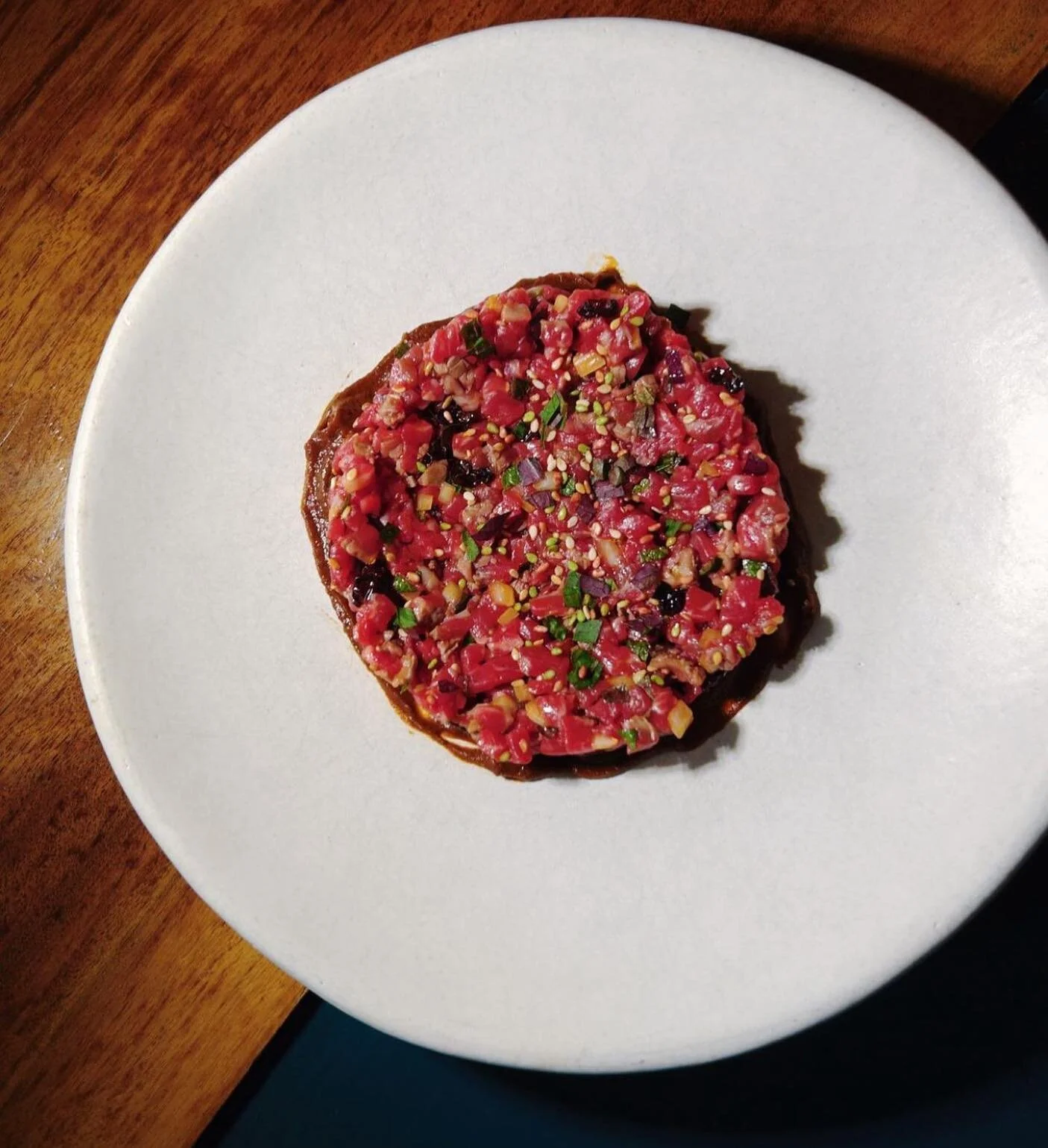Wagyu Striploin barely seared and chopped up into a tartare. Served with a quince mole, sesame seeds, shiso leaf and onions.