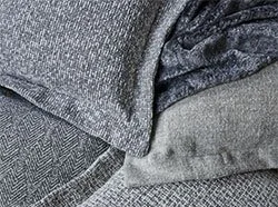Close-up of various folded fabric fabrics in gray and black tones.