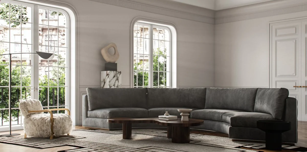 Living room with large windows, a gray sectional sofa, a furry armchair, a wooden coffee table, and modern wall art.