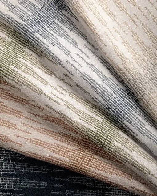 Close-up of fabric with horizontal stitched patterns in multiple colors including beige, ivory, gray, and black.