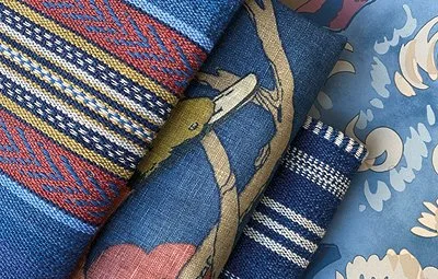 Close-up of rolled fabric with various traditional patterns and colors in blue, yellow, red, and beige.