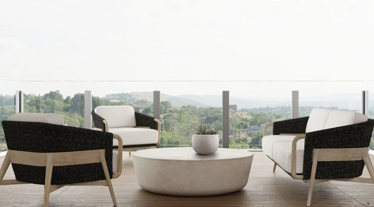 Modern outdoor patio with four chairs and a round coffee table, overlooking a scenic landscape with hills and greenery.