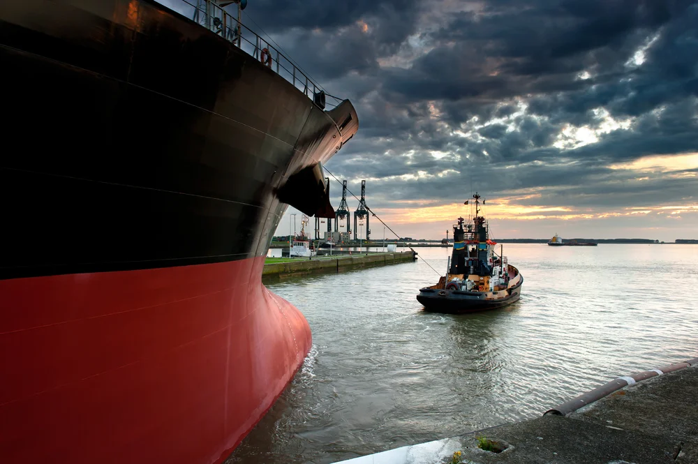 A tug boat taking out a ship from harbor