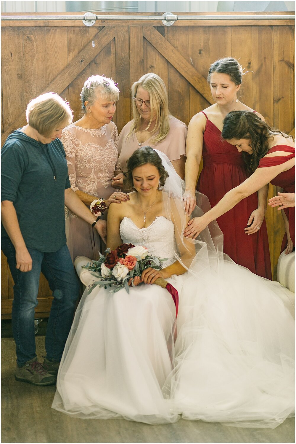  bride praying with her bridesmaids and family 