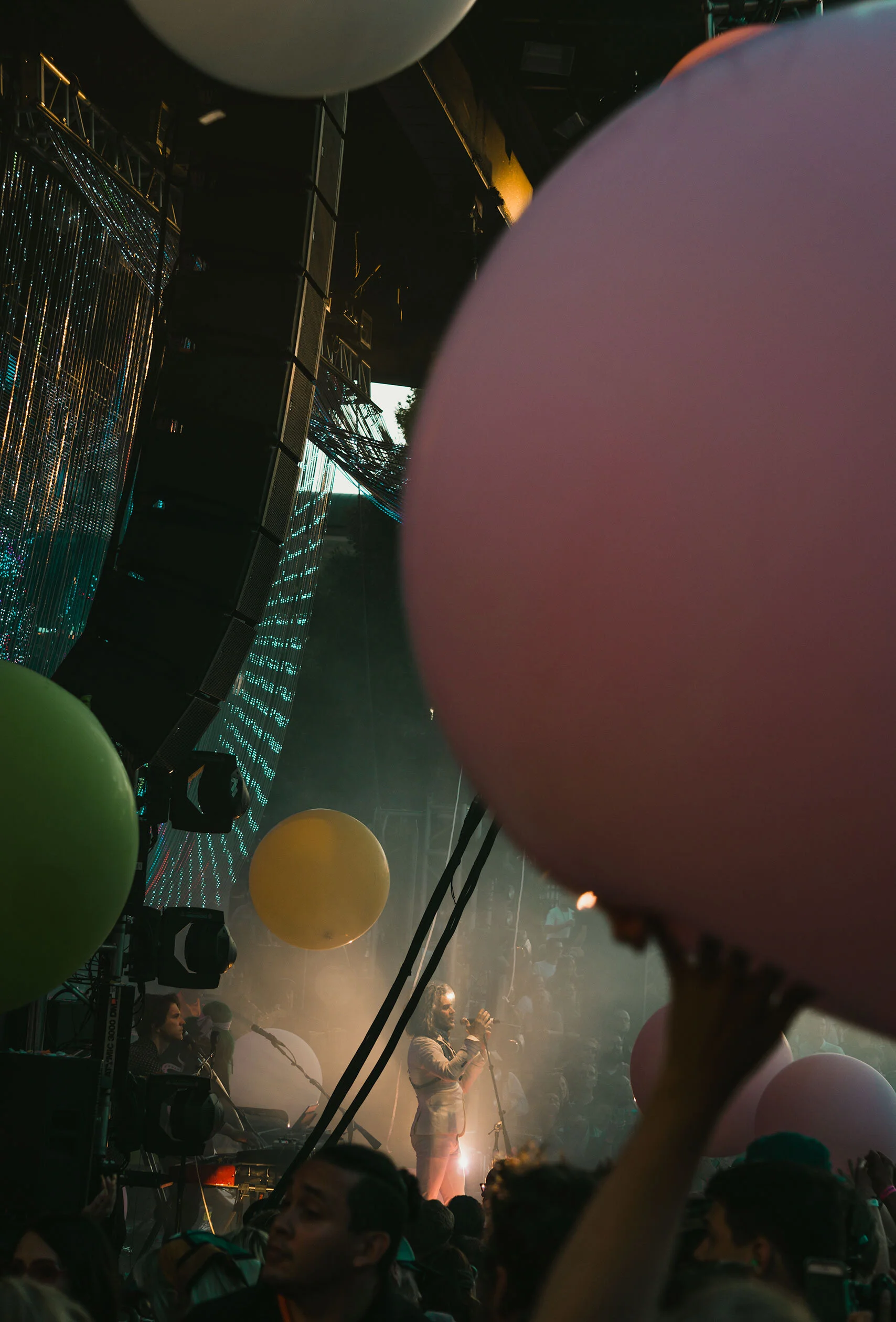 Balloons, appendages, and wires frame The Flaming Lips onstage surrounded by fog illuminated by golden hour light. The Flaming Lips in Ogden, Utah.