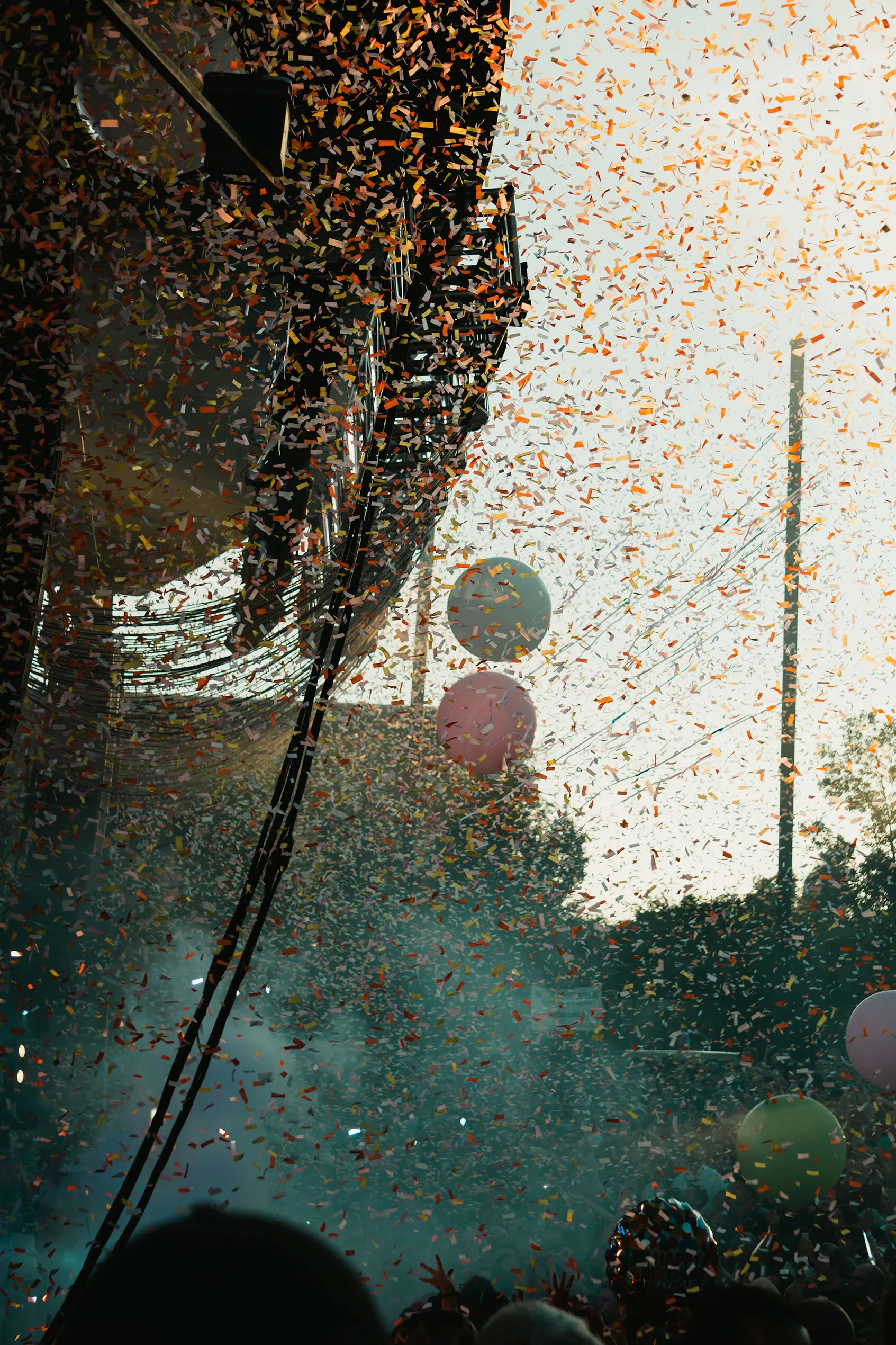 Colorful fog, confetti, and balloons glow in golden hour light while cool shadows surround stage and crowd. The Flaming Lips in Ogden, Utah.