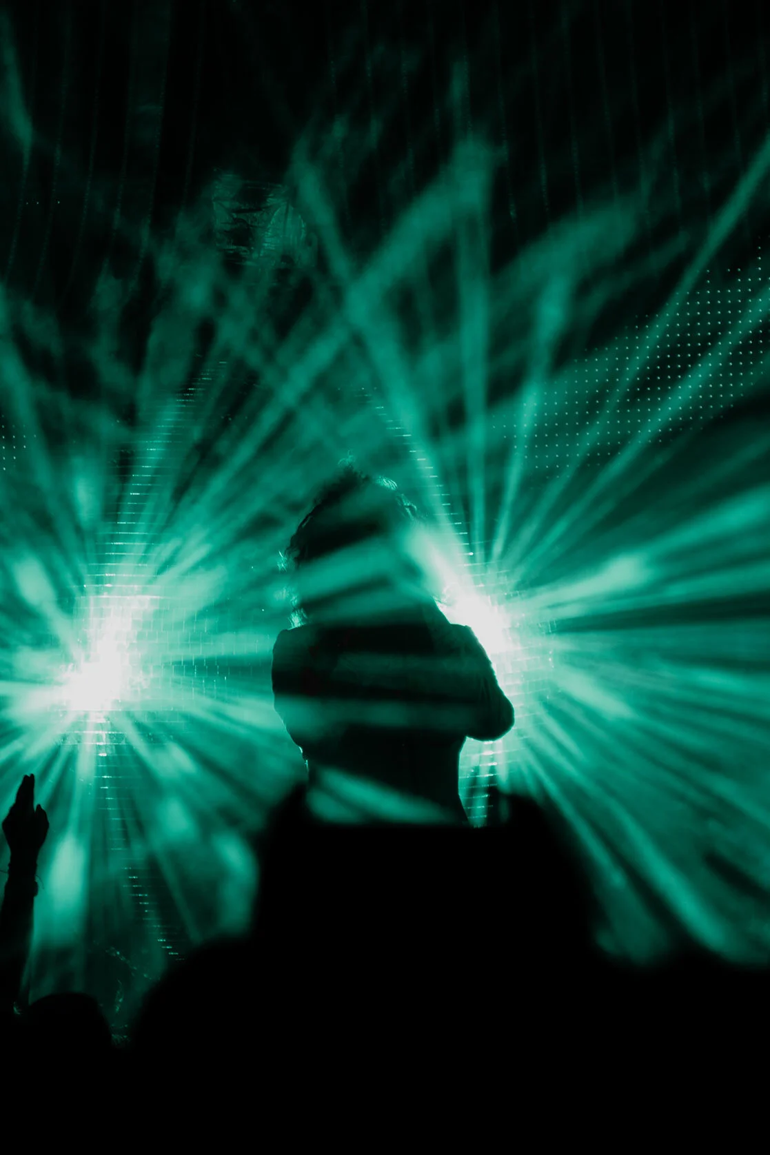 The Flaming Lip's lead singer and the crowd are silhouetted by rays of teal light bouncing off a large disco ball onstage. Ogden, Utah.