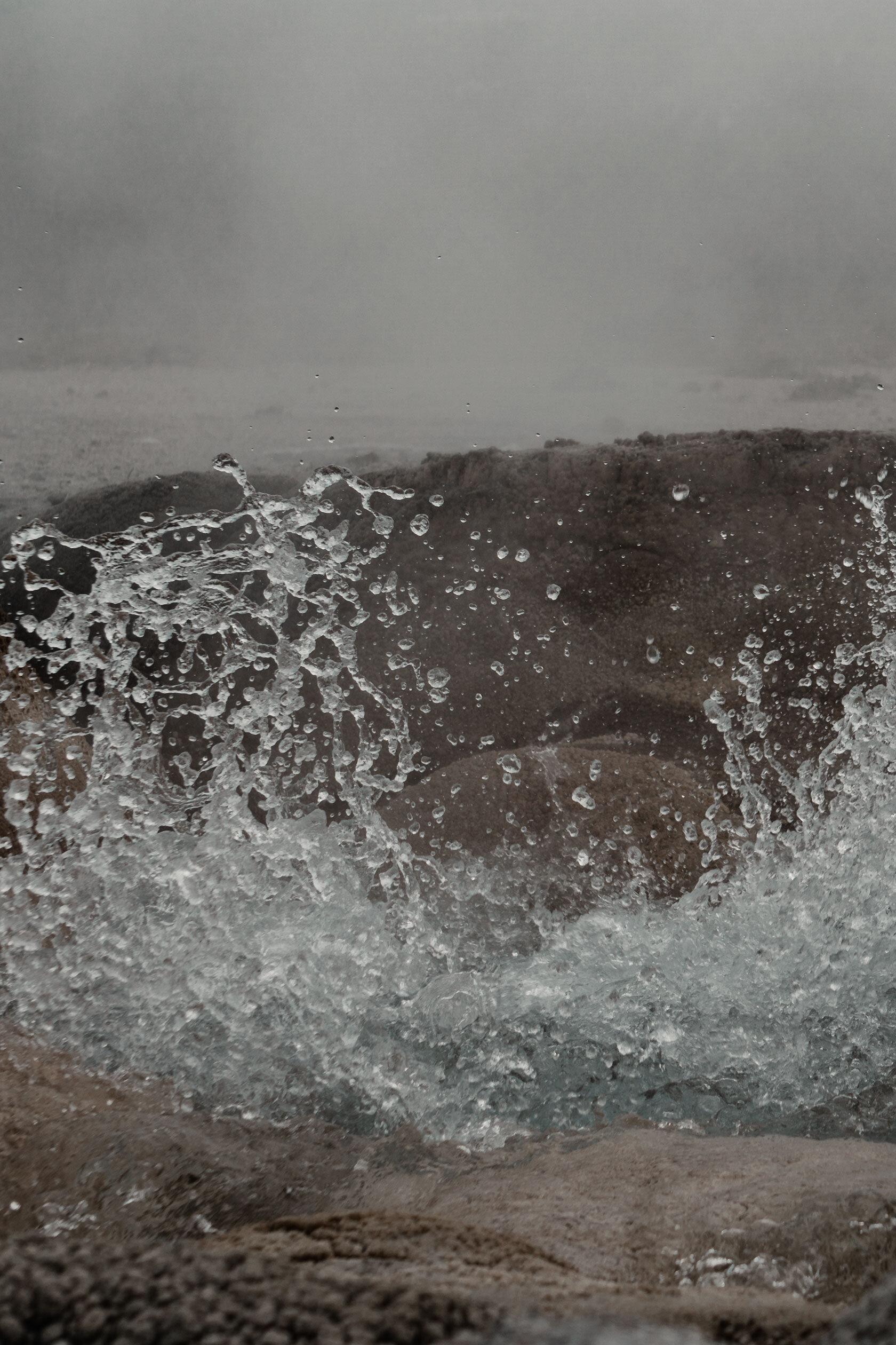 hot spring spraying boiling water whilst surrounded by its own fogy steam in brown mineral stone pool. Yellowstone National Park, Montana.