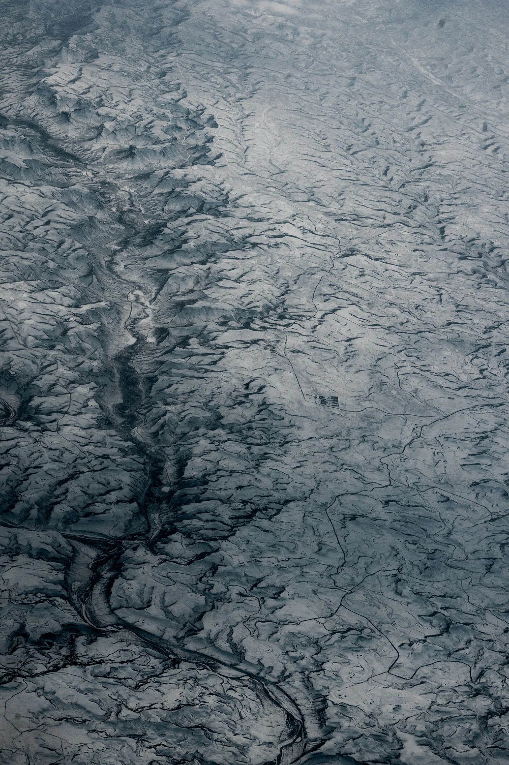 Arial view of snow covered mountainous landscape. Winding canyon with a road at the base winds along the left third somewhere in the United States of America.