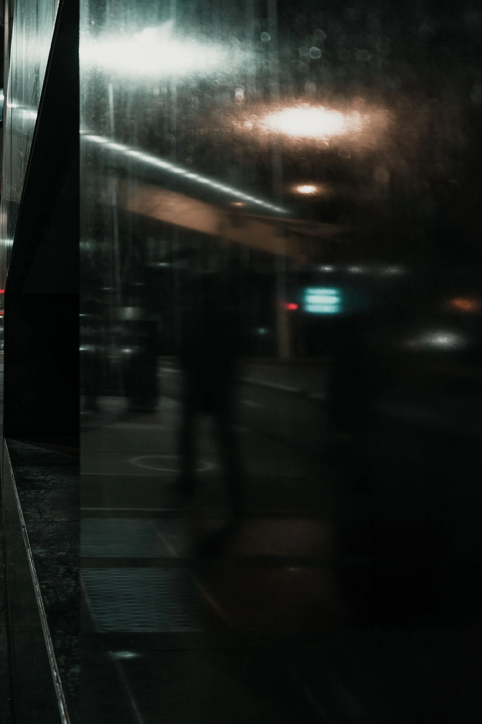 Blurred people walking down a street in Atlanta, Georgia. The scene is reflected in the black granite wall occupying the opposite half.